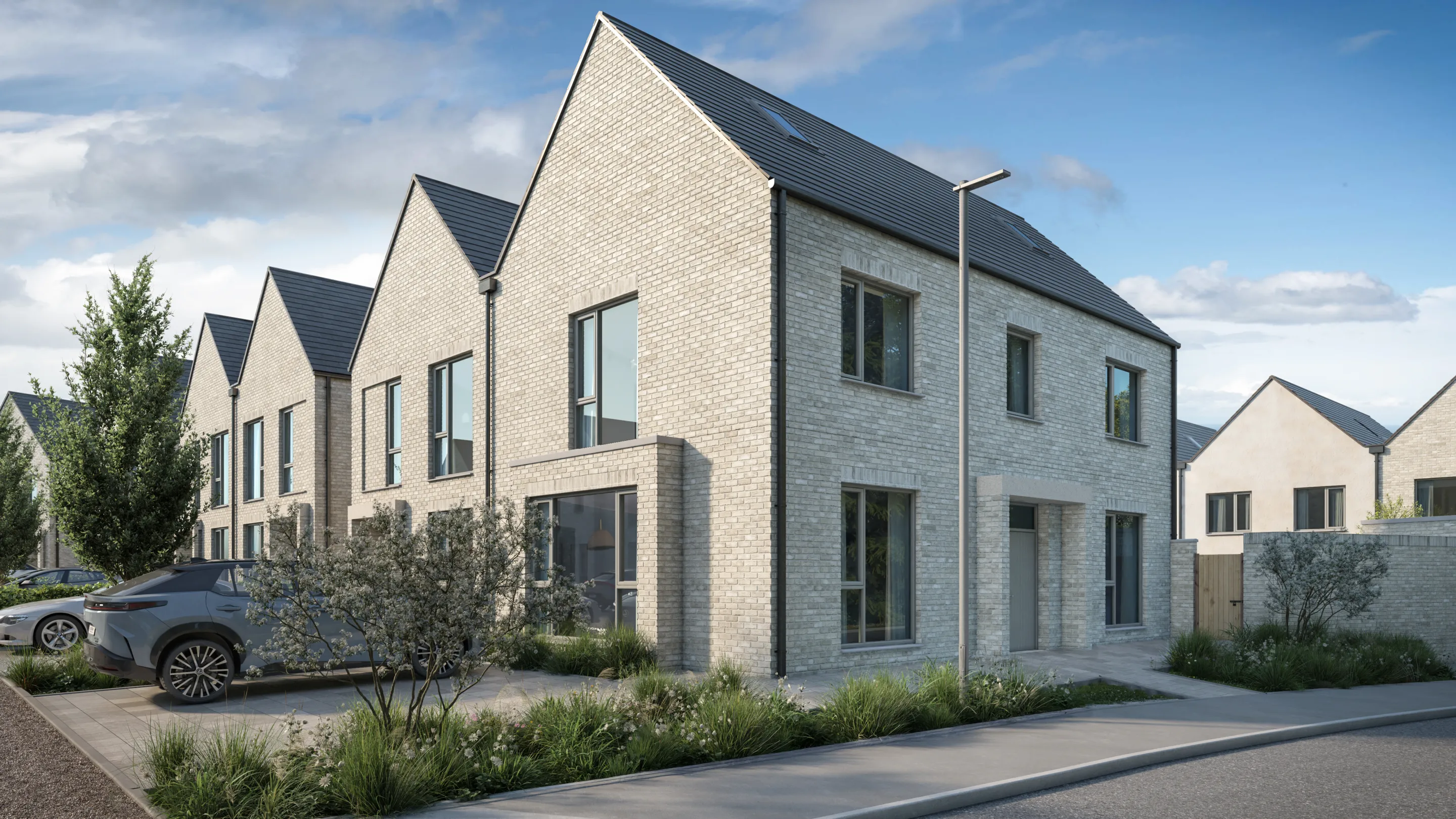 A row of modern terraced houses with landscaping and cars in the driveway