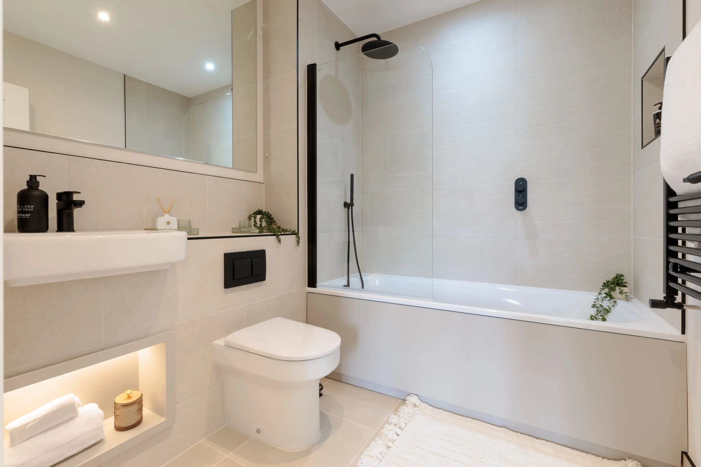 A modern bathroom with a bath, toilet, sink, and minimal decor.