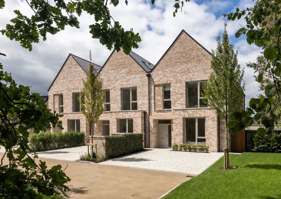 Two modern brick houses stand side-by-side with symmetrical designs and greenery enhancing the surrounding landscape.