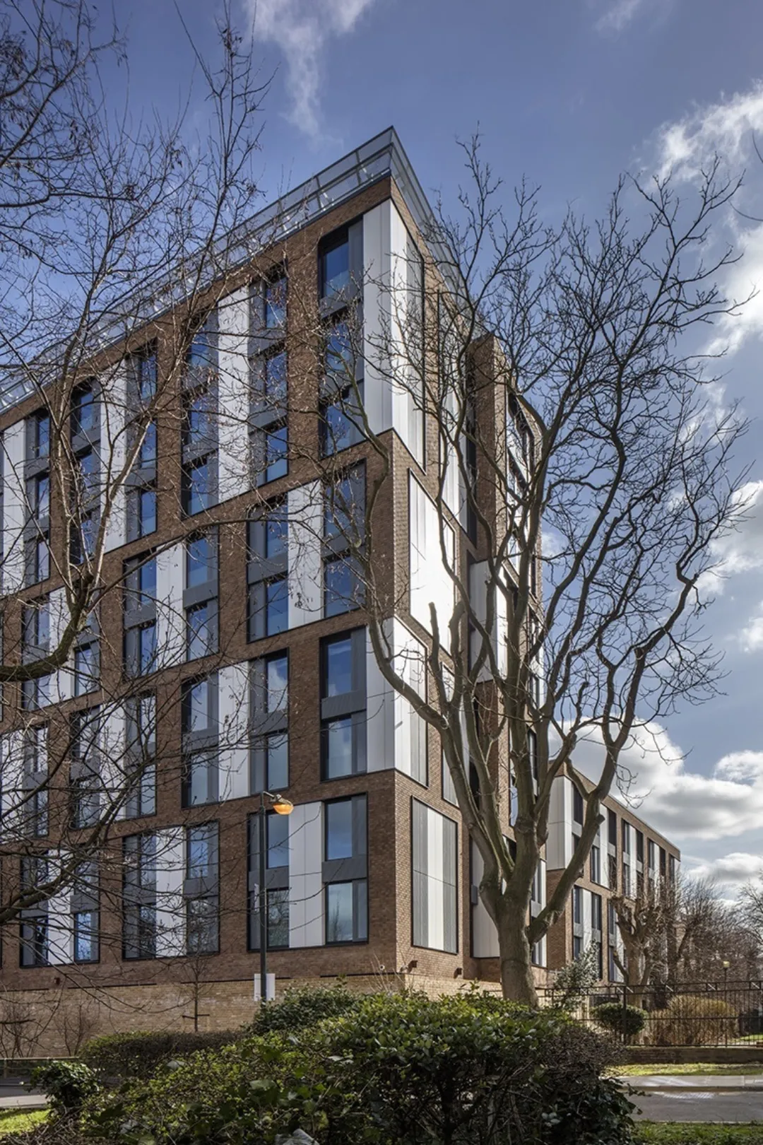 A modern multi storey building seen from the corner through bare trees