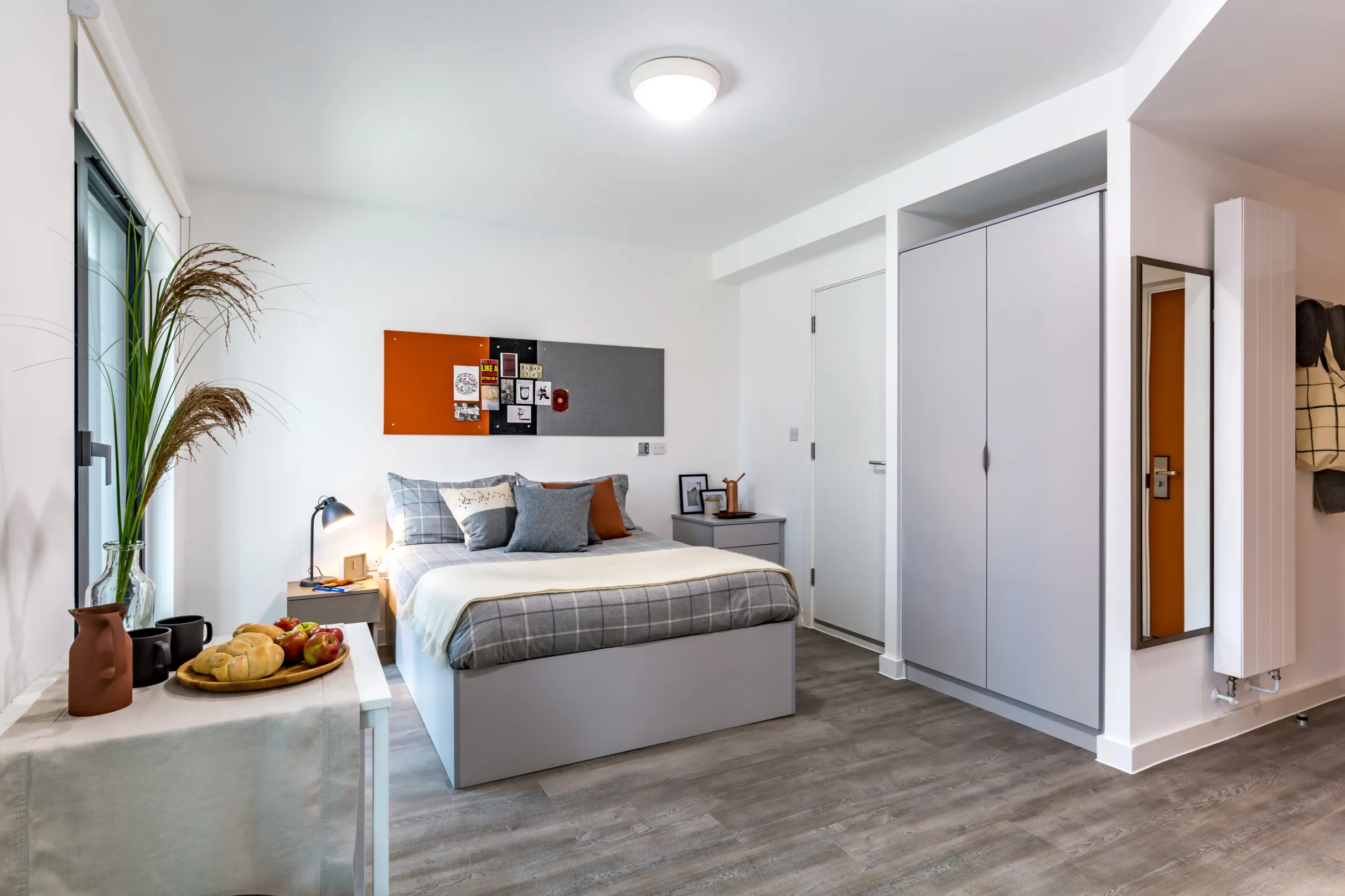 Studio room in a student accommodation block showing a bed, wardrobes and a long wall mirror