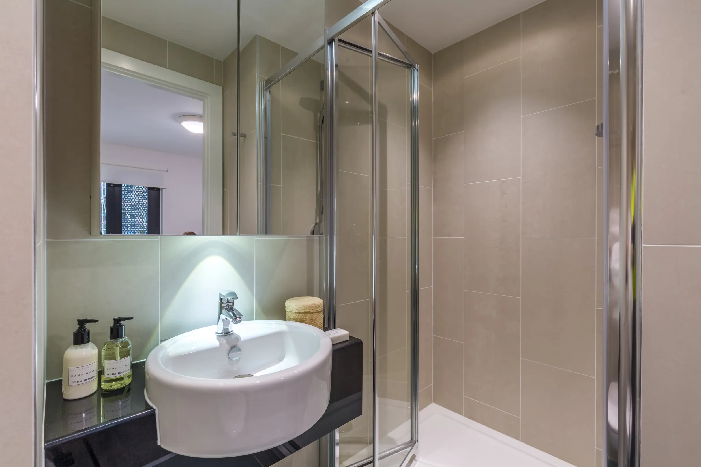 Student accommodation ensuite showing a shower and basin with mirror above