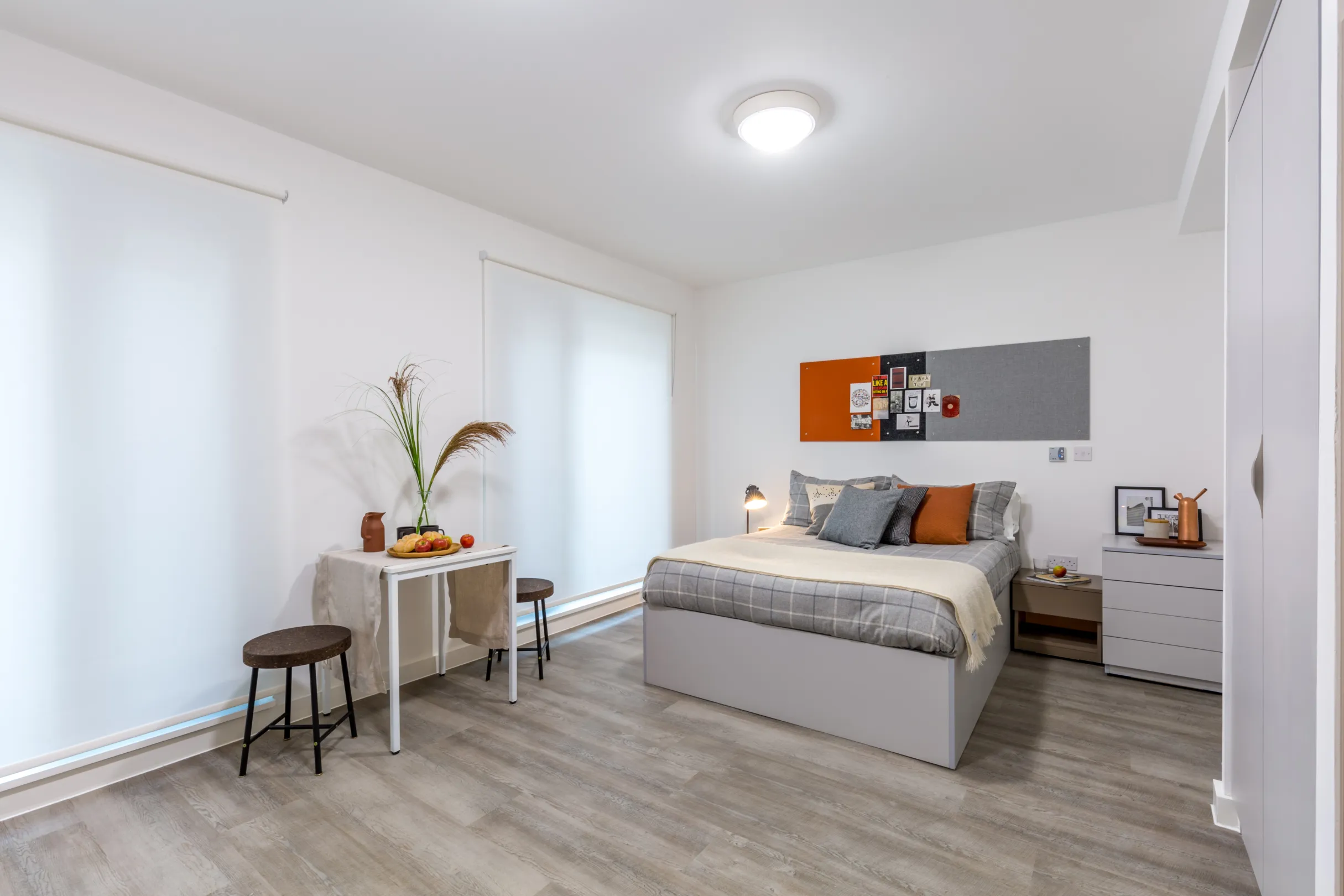 Studio room student accommodation showing a double bed and side drawers, wardrobe and dressing table