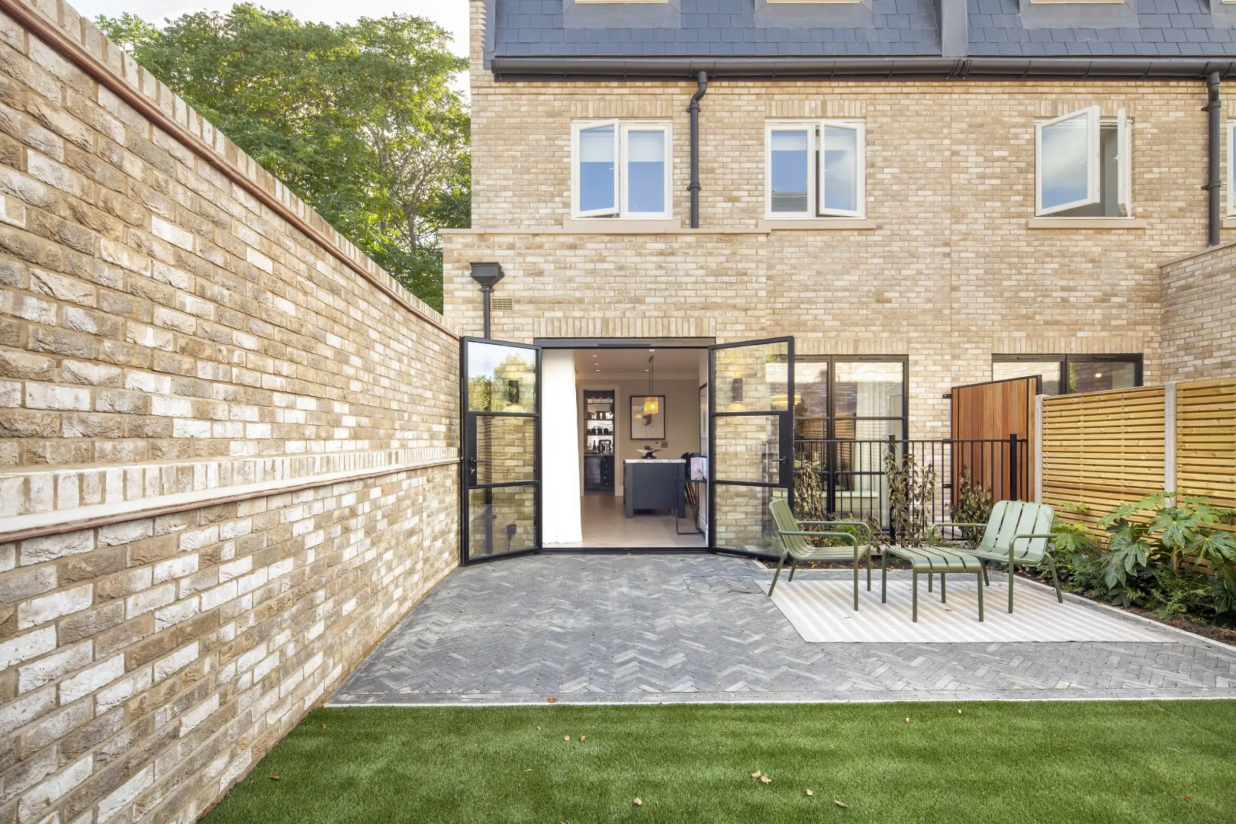 Rear garden: A private landscaped garden with herringbone paving and Crittall-style doors opening straight into the kitchen.