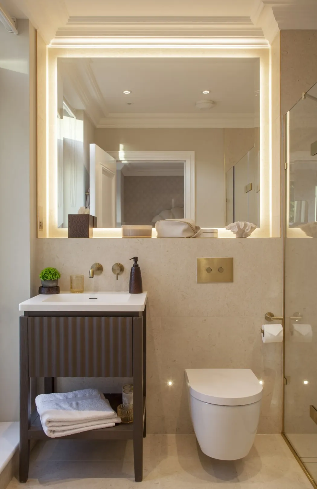En suite shower room: A backlit mirror, warm limestone tiling and brushed brass fittings bring a boutique-hotel feel to the principal en suite.
