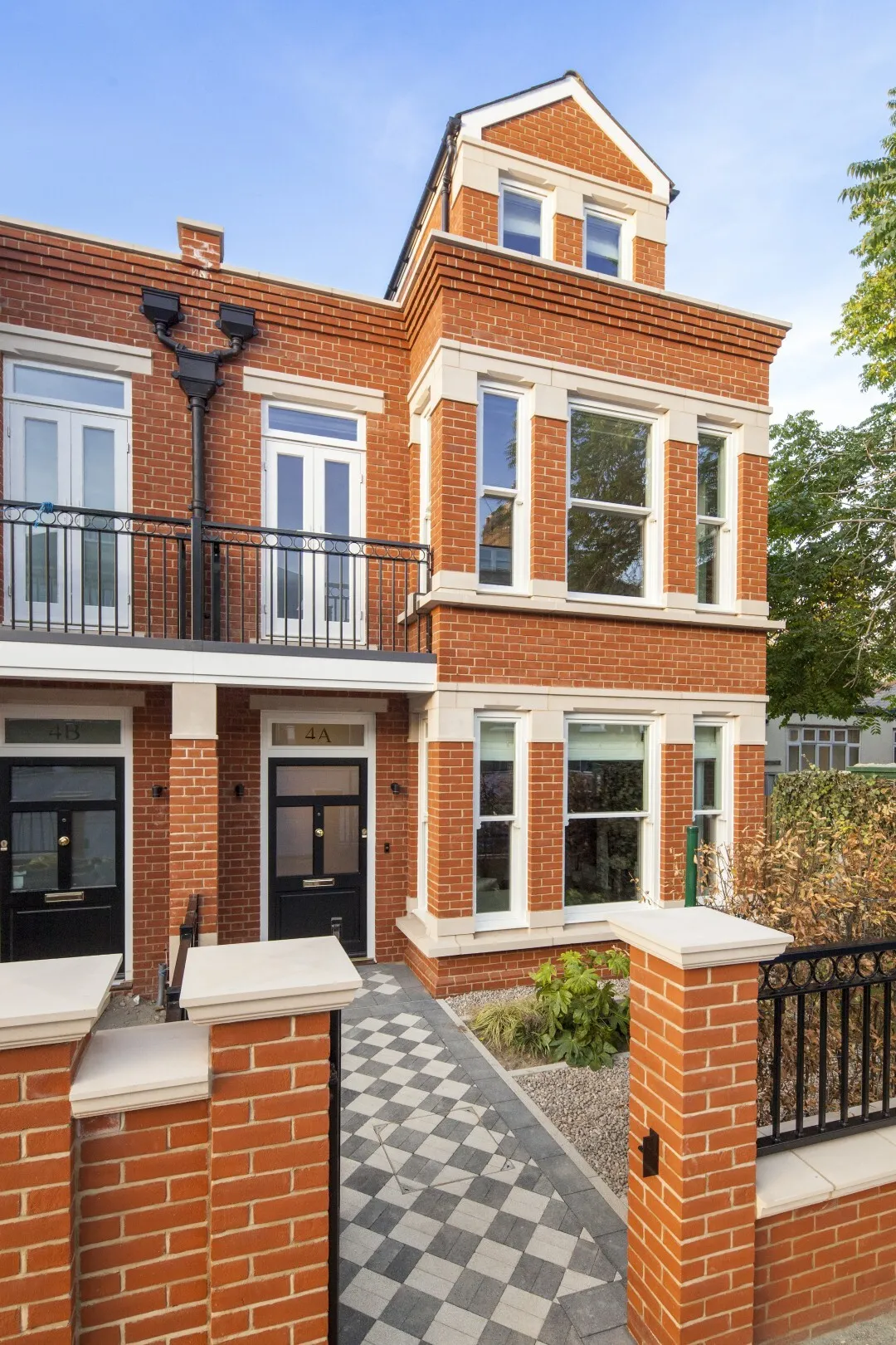Front exterior (gated entrance): A handsome red-brick façade with stone detailing, sash windows and a chequerboard path leading to a classic black front door.