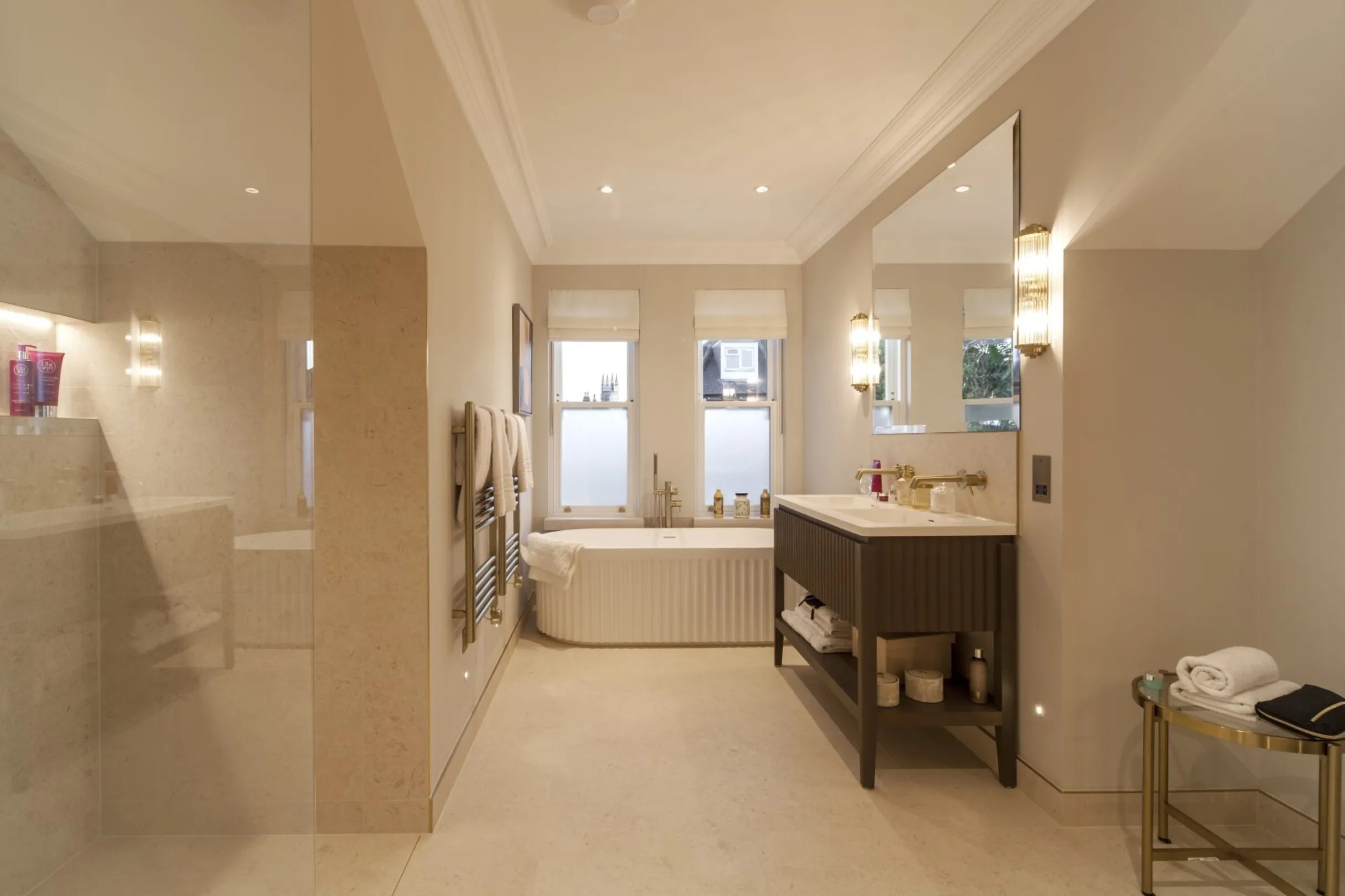 Top-floor bathroom: A spa-like sanctuary with a fluted freestanding bath, walk-in shower and double vanity beneath elegant sloping eaves.