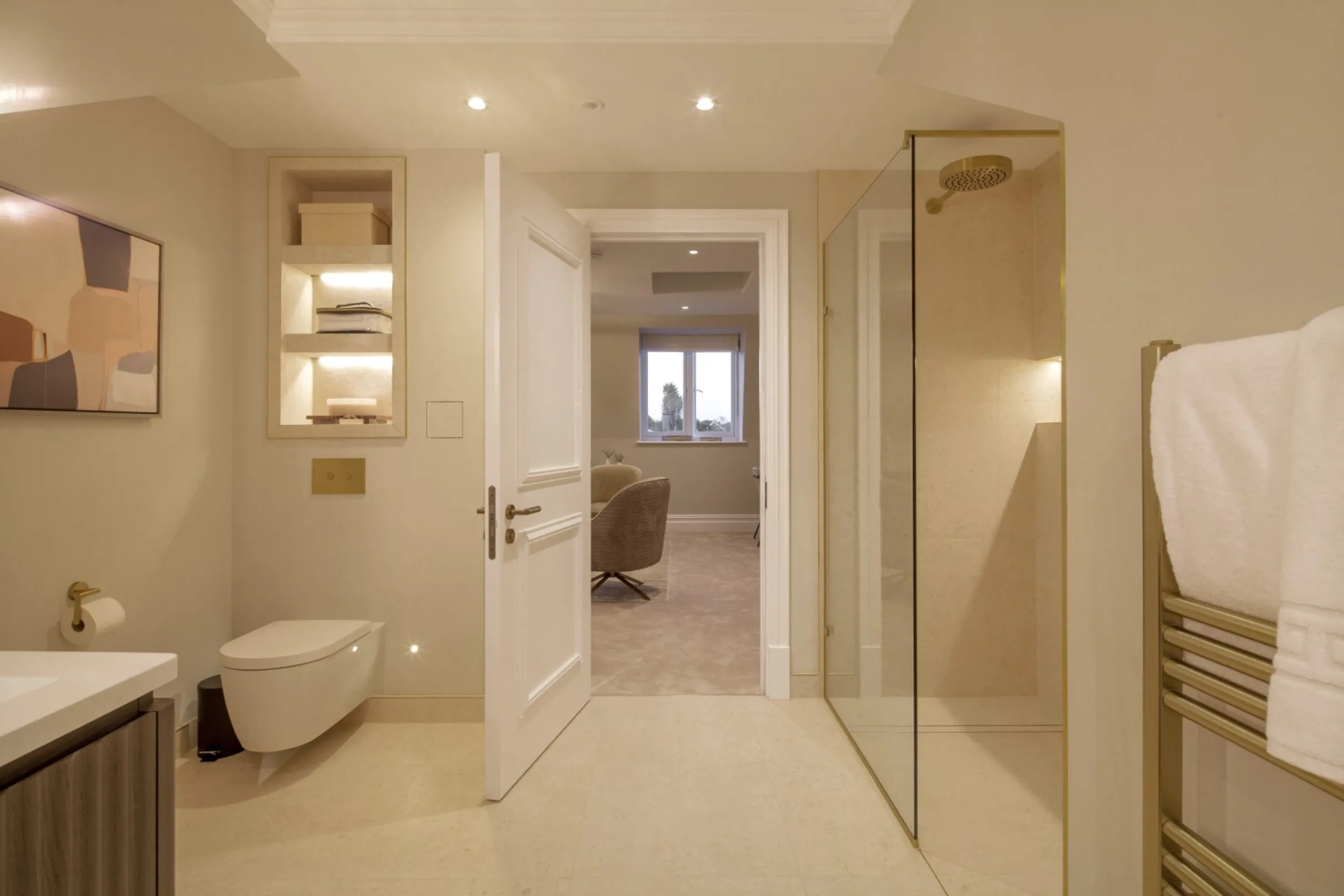Master en suite (bedroom view): A walk-in rainfall shower, illuminated stone niche and brushed brass details flow seamlessly through to the master bedroom.