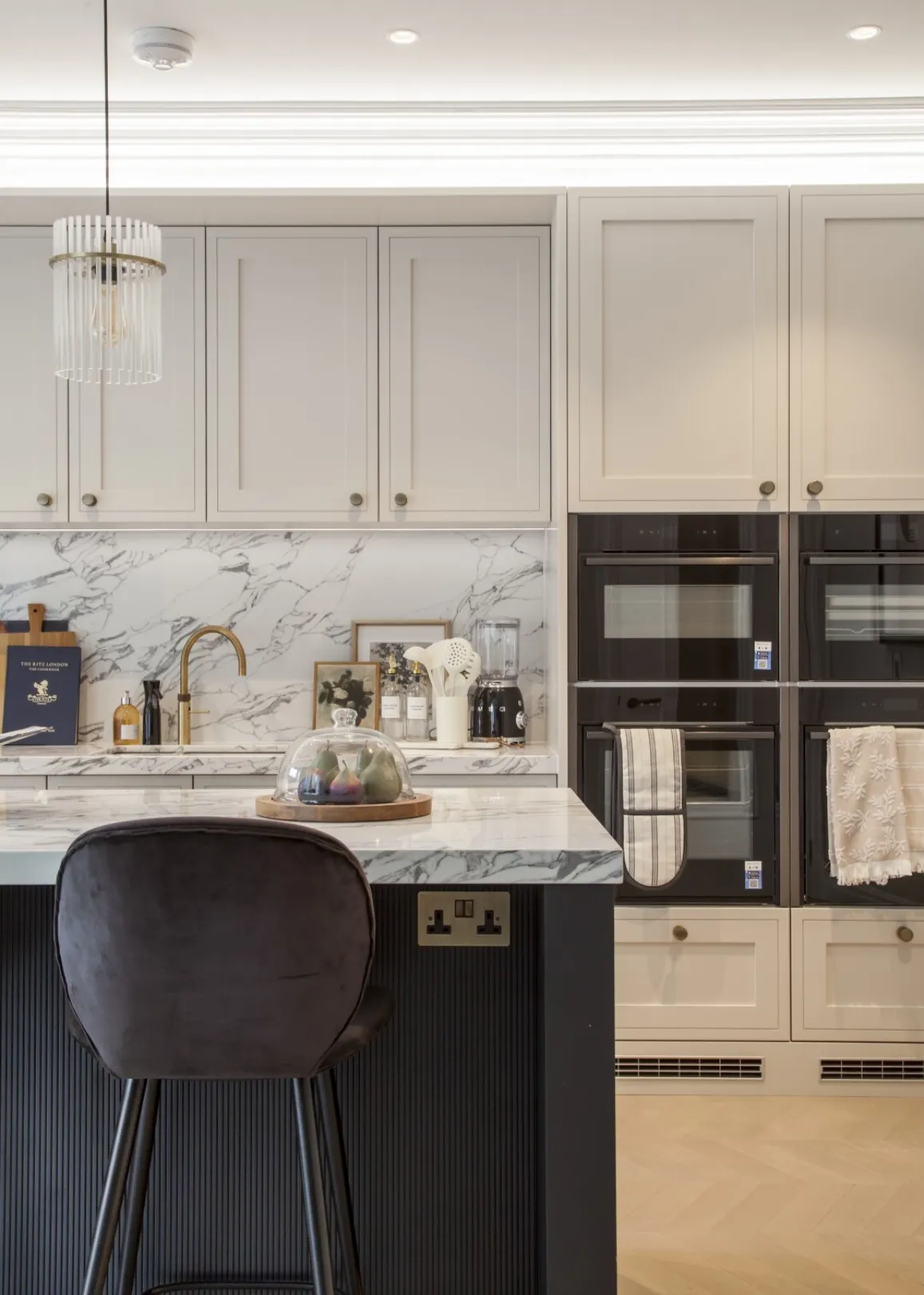 Kitchen detail: Marble-effect worktops, a brass boiling-water tap and a bank of integrated ovens combine style with serious cooking credentials.