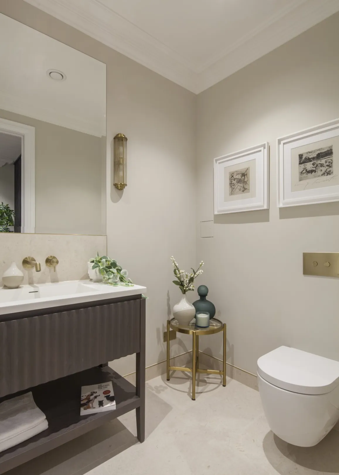 Lower-ground cloakroom: A refined WC with a fluted vanity, brushed brass fittings and curated artwork for a gallery-like finish.