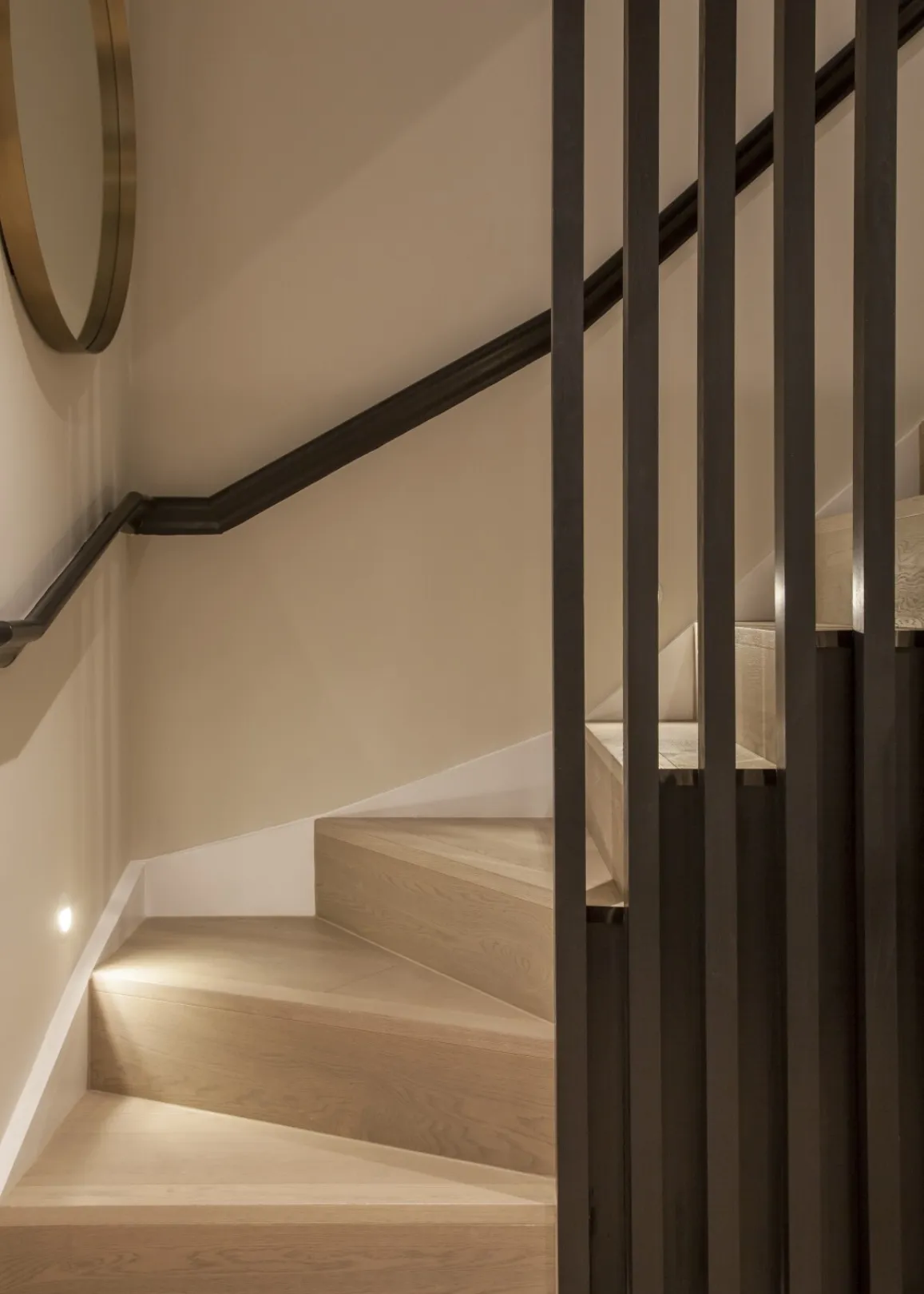 Staircase detail: Solid oak effect treads, low-level lighting and a dark slatted timber screen give the staircase to the lower ground a crafted, contemporary edge.