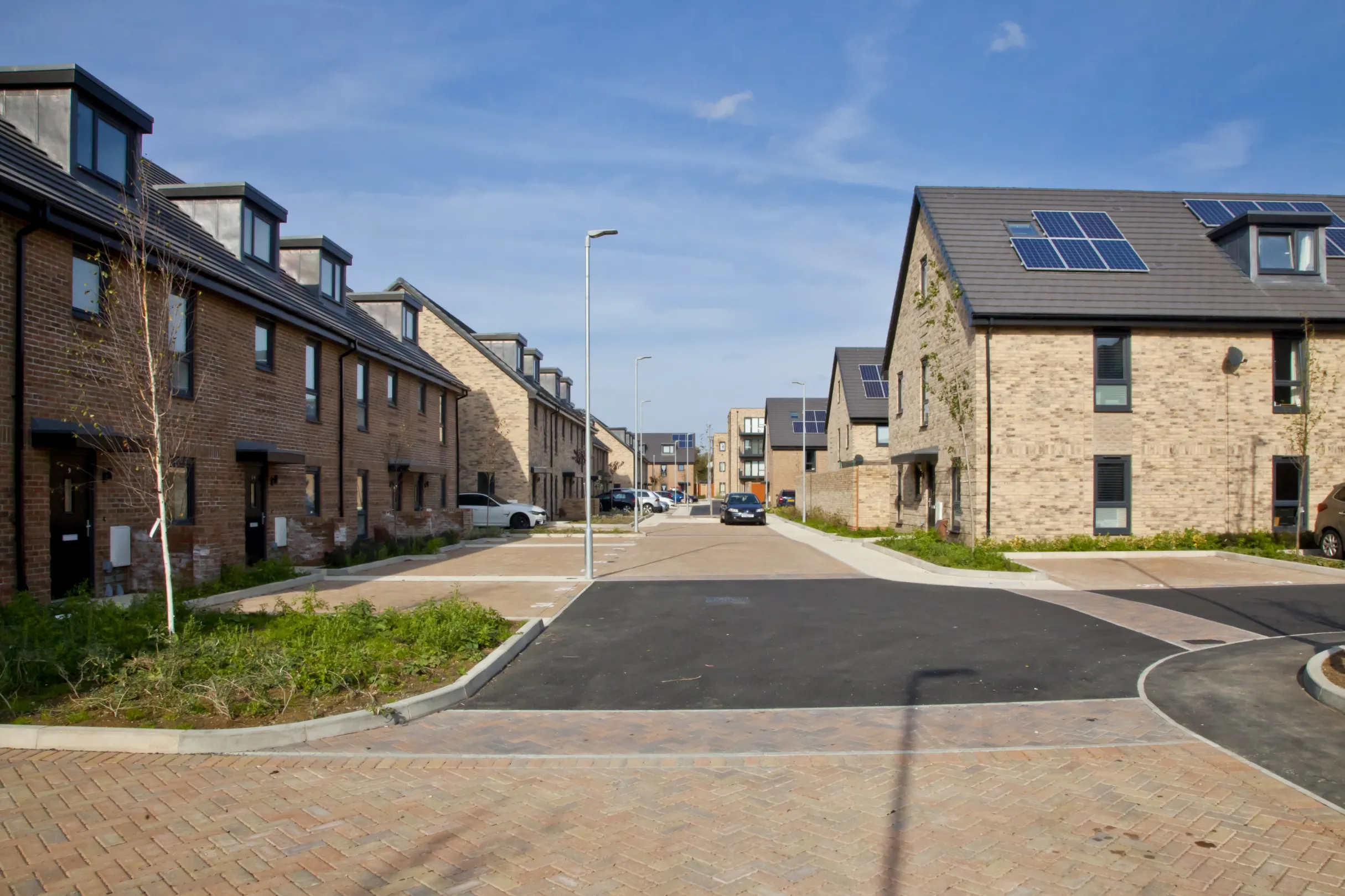Three modern terraced homes built in brick with dormer windows and solar panels