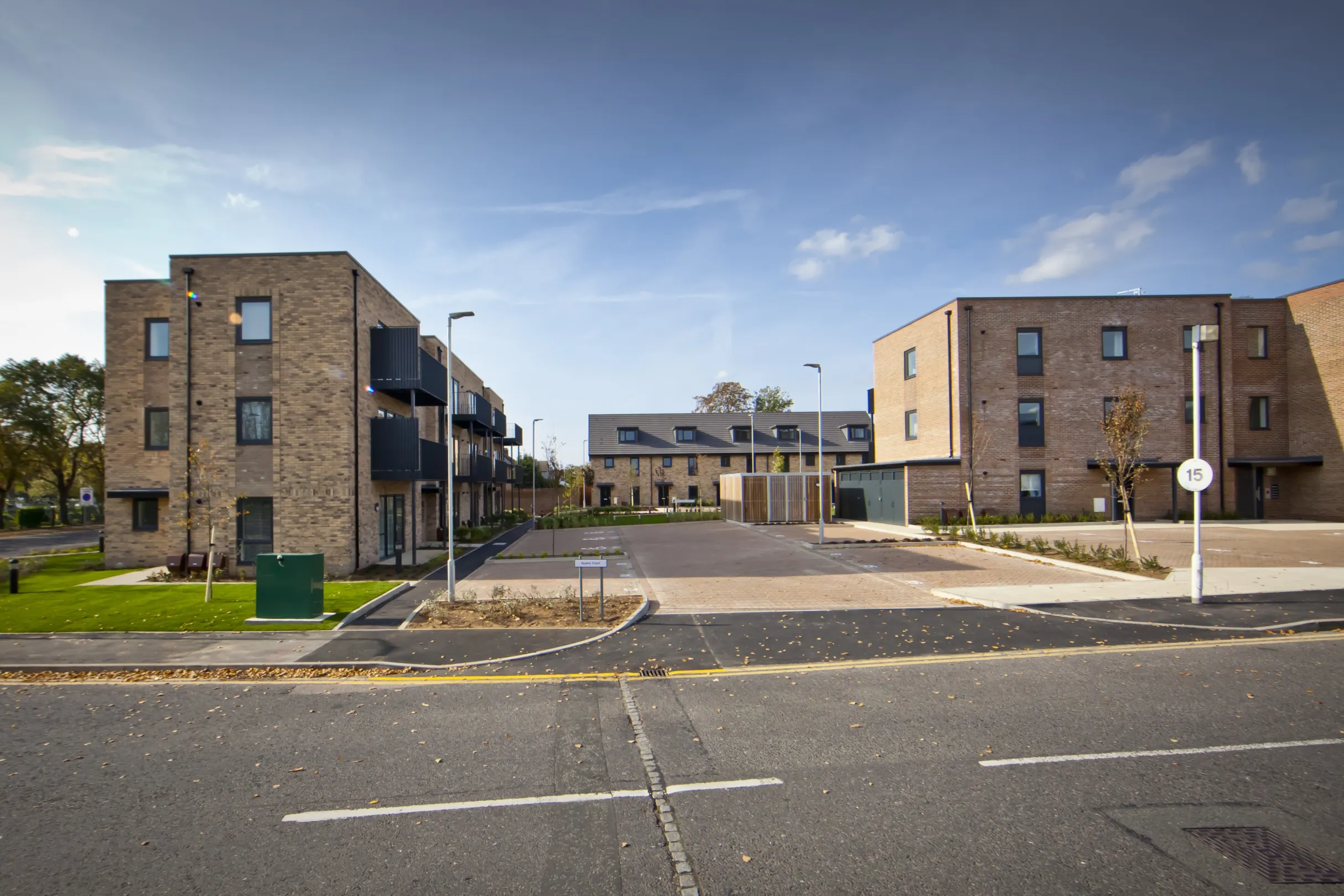 Modern low-rise flats in a residential development overlooking central parking area and street lighting with green space to the side