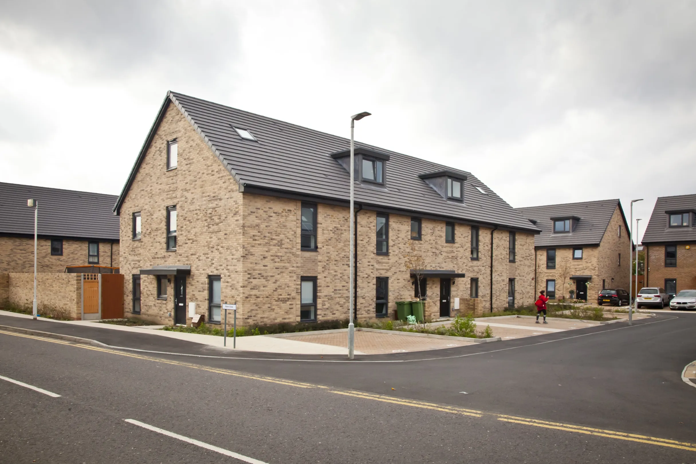 Modern terraced homes built in brick with dormer windows and off-street parking.