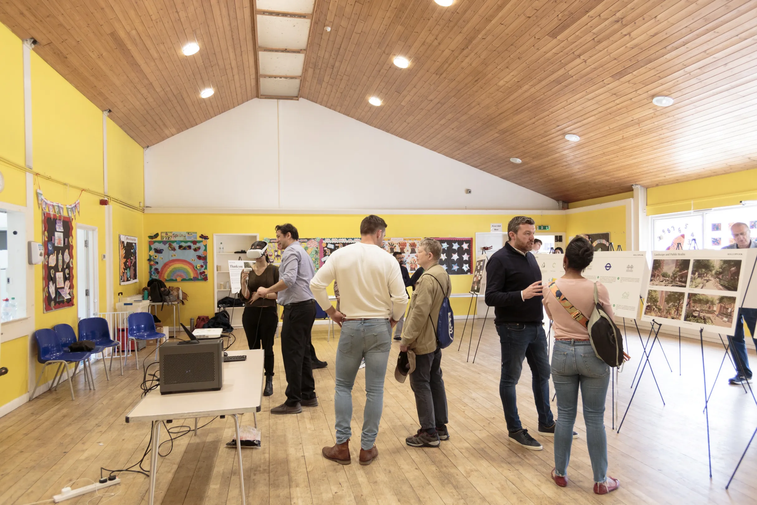 A public consultation with illustration boards around the room and members of the public reading and looking at the boards