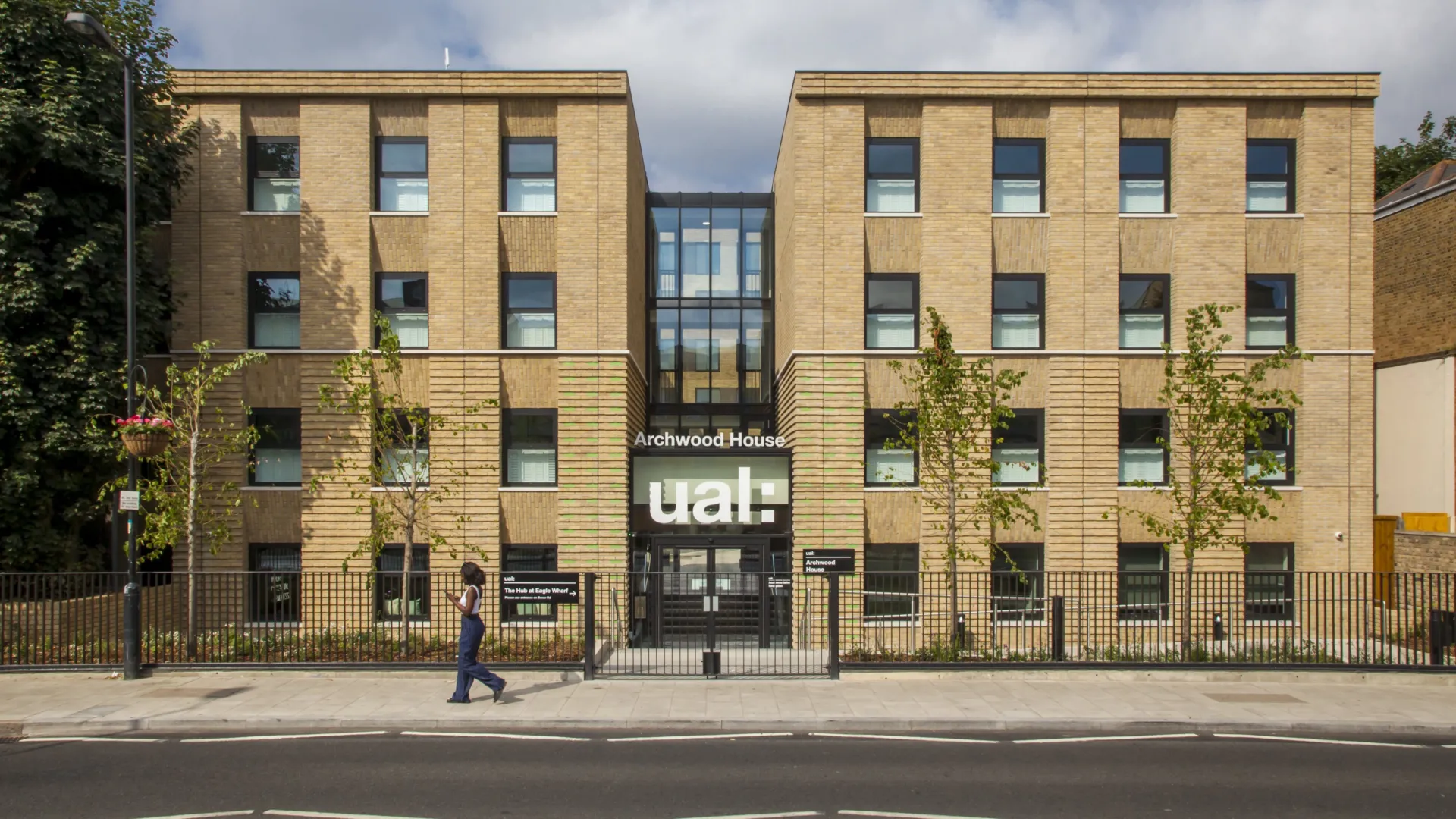 Facade of a modern four story building with central glazed atrium. A prominent sign above the door reads: Archwood House UAL
