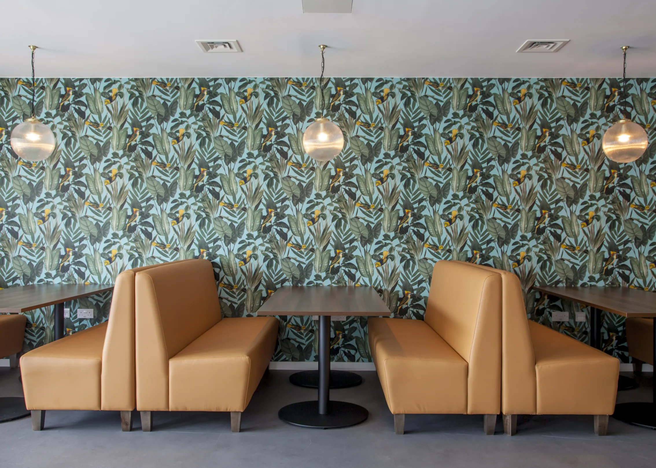booth-style seating with ornate avian patterned wallpaper and ribbed glass pendant lighting