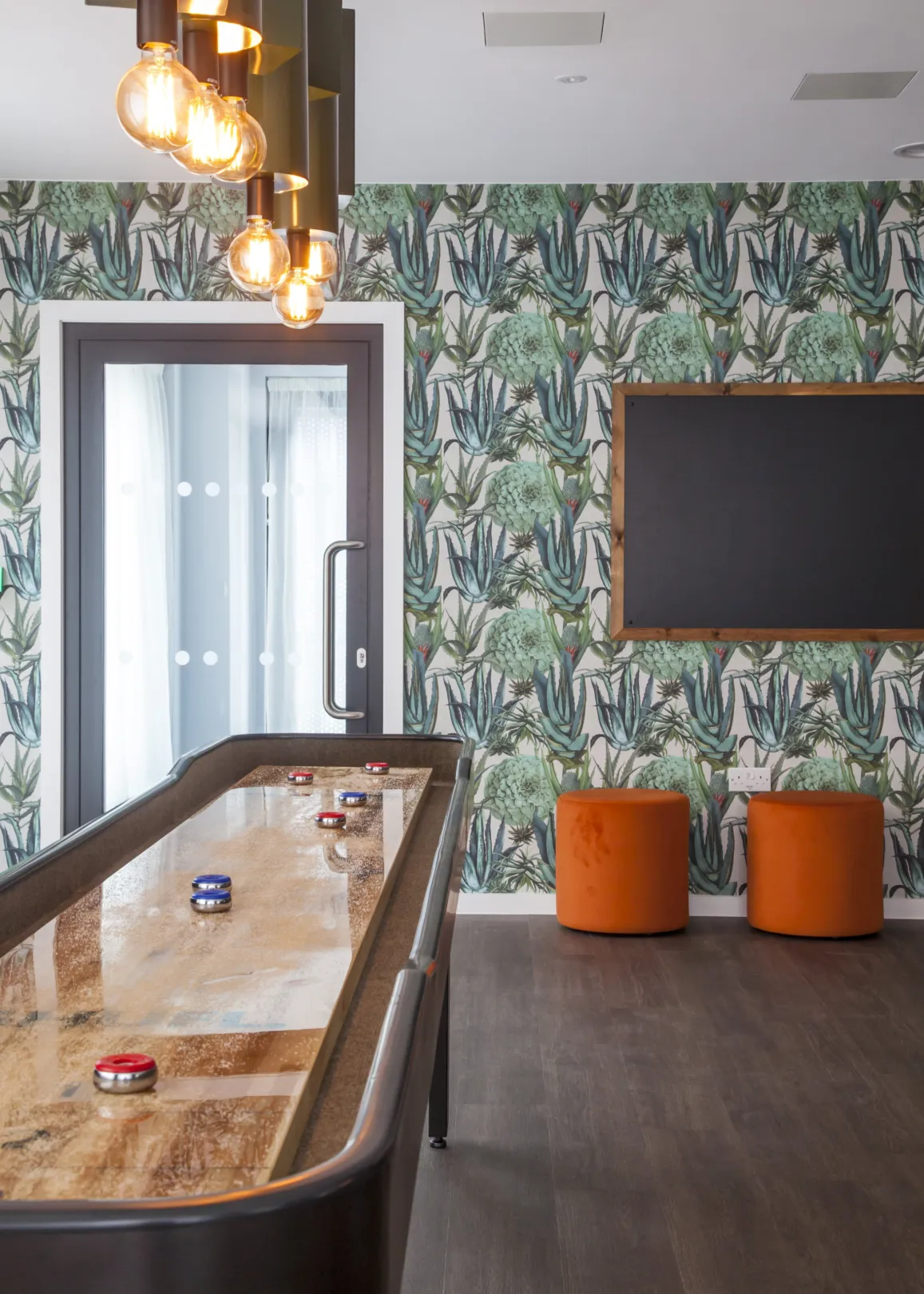 A modern shuffleboard table and ornate avian wallpaper on a student accommodation social area