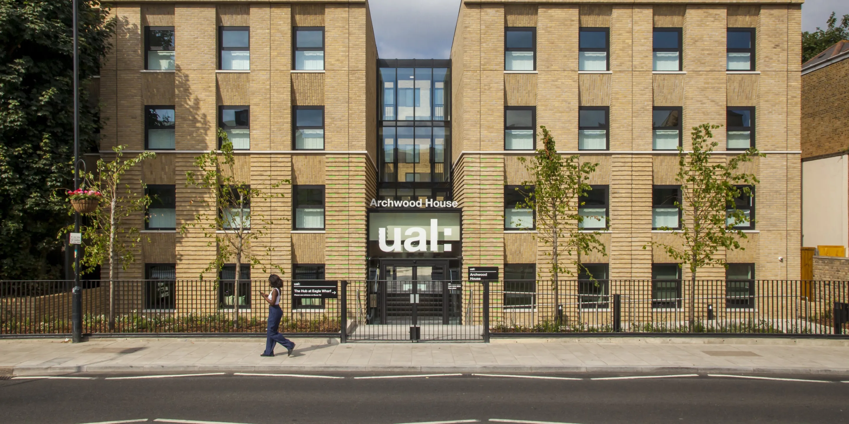 Facade of a modern four story building with central glazed atrium. A prominent sign above the door reads: Archwood House UAL