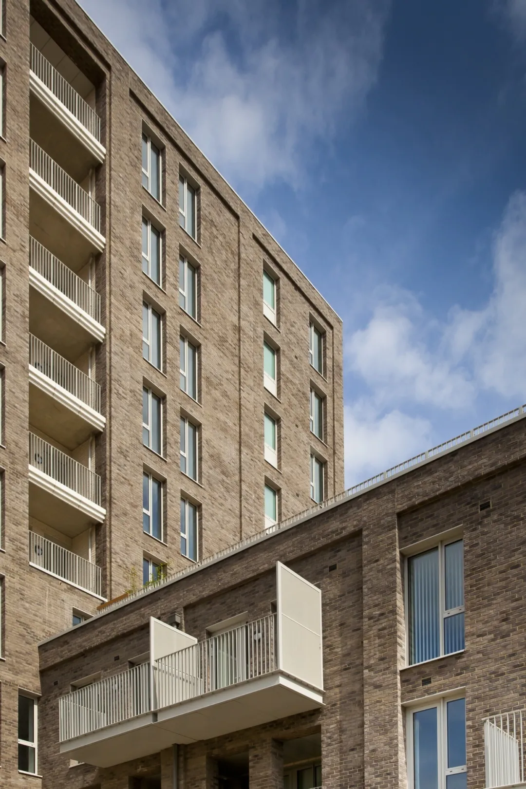 A modern multi storey residential building with balconies and a smaller building of the same development in the foreground.