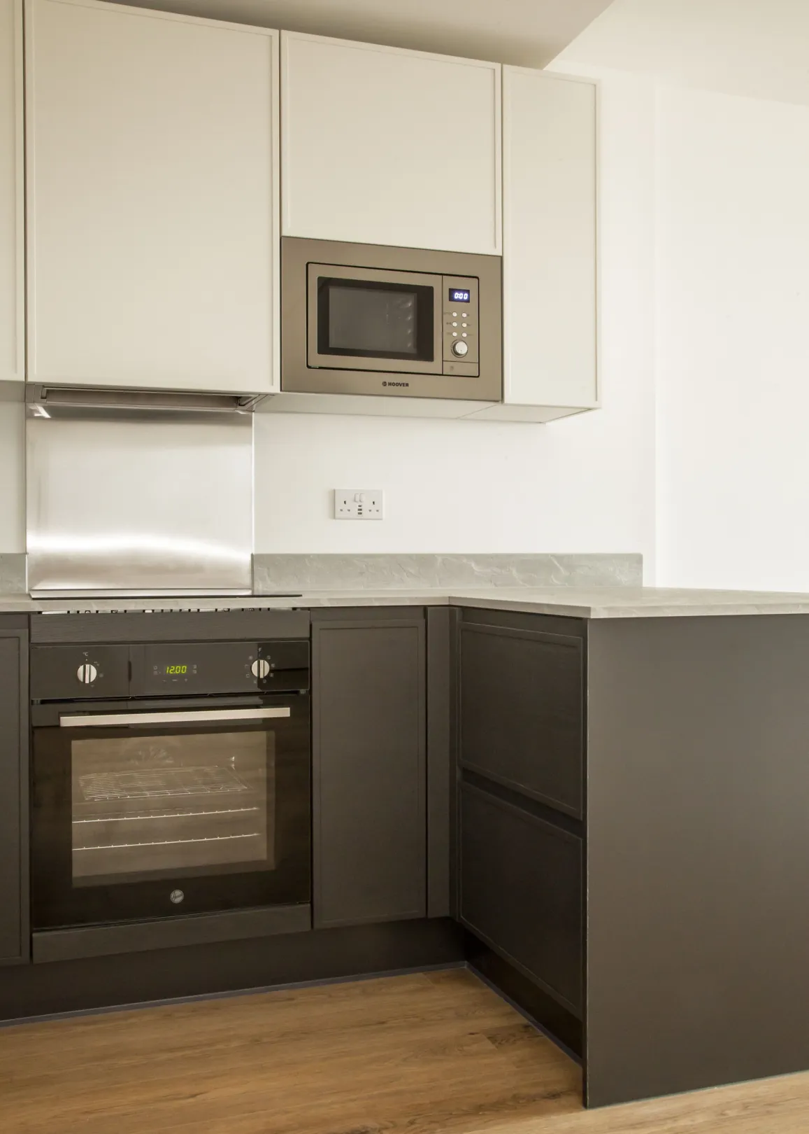 Modern kitchen with cooker, stovetop and built-in microwave.