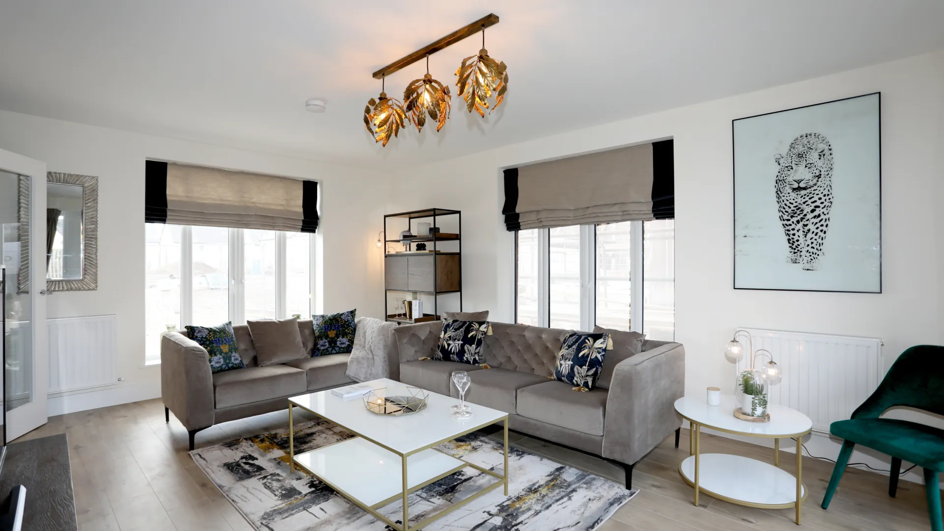 A modern large living room with dark wallpaper on a feature wall, large windows, wood flooring, TV, sofa and side table
