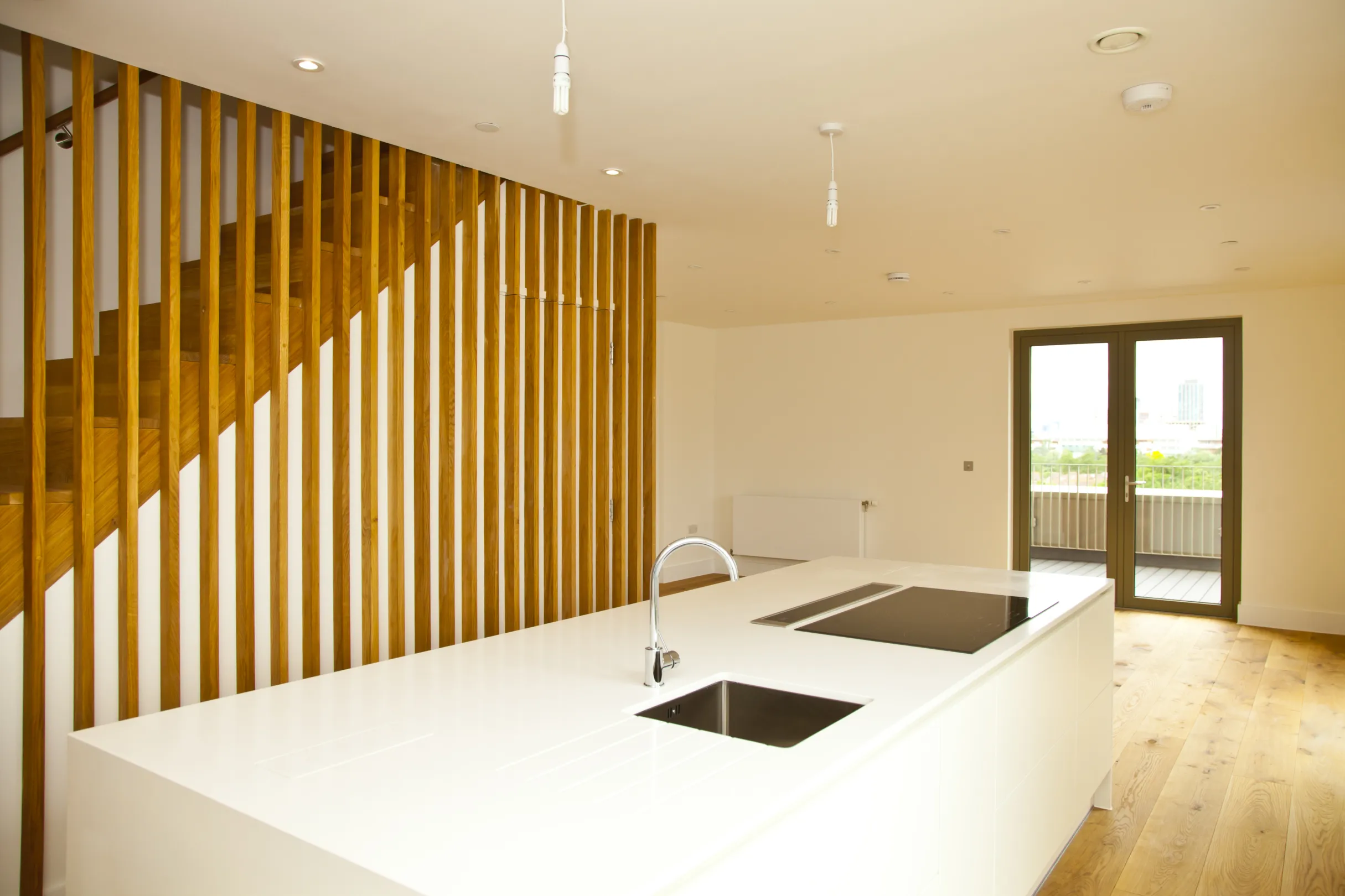 Architectural detail of a modern wooden staircase with floor to ceiling balustrade and a handrail to the wall
