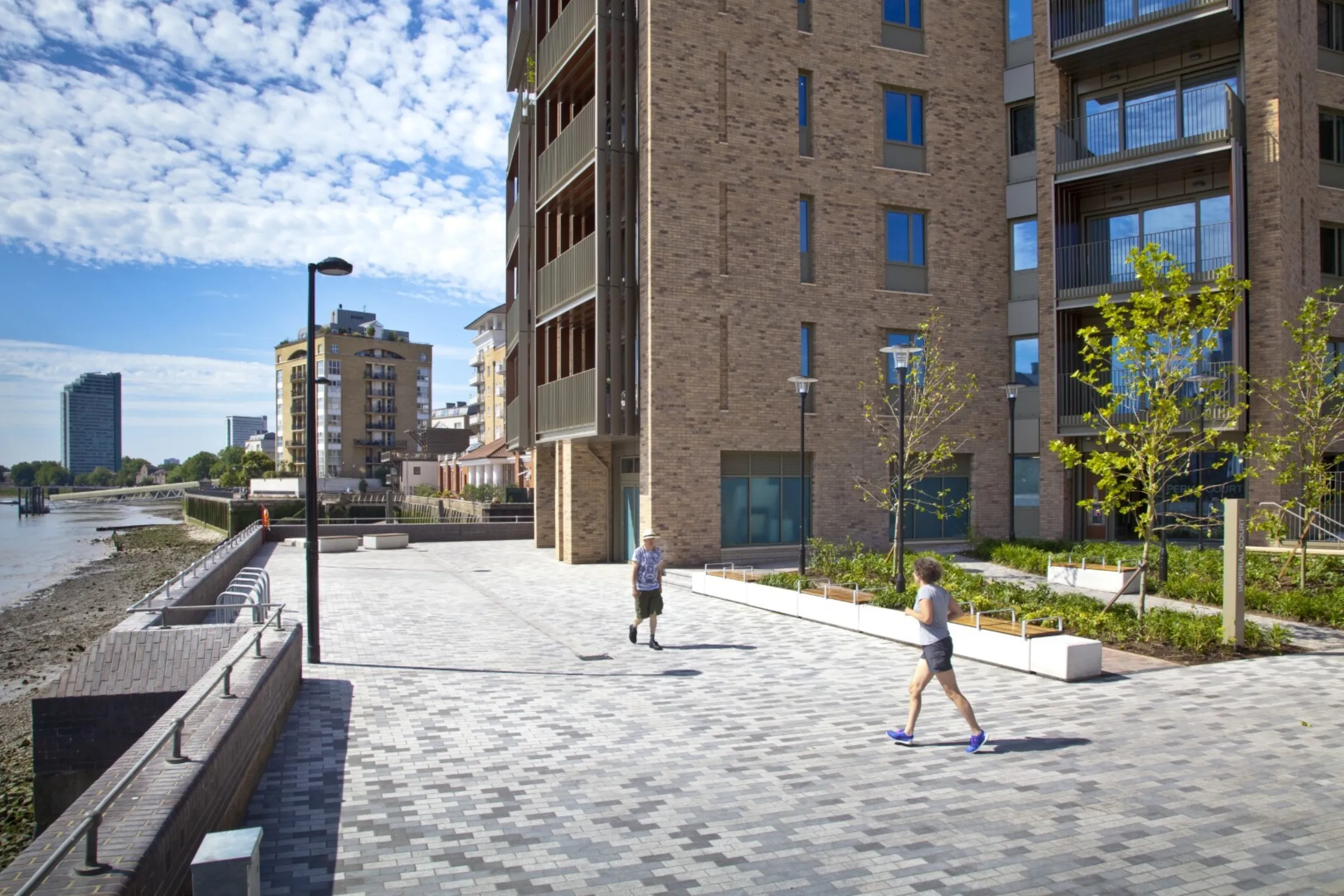 Detail of the lower floors of a modern multi storey residential building on the bank of the River Thames. Skyscrapers are visible on the opposite bank.