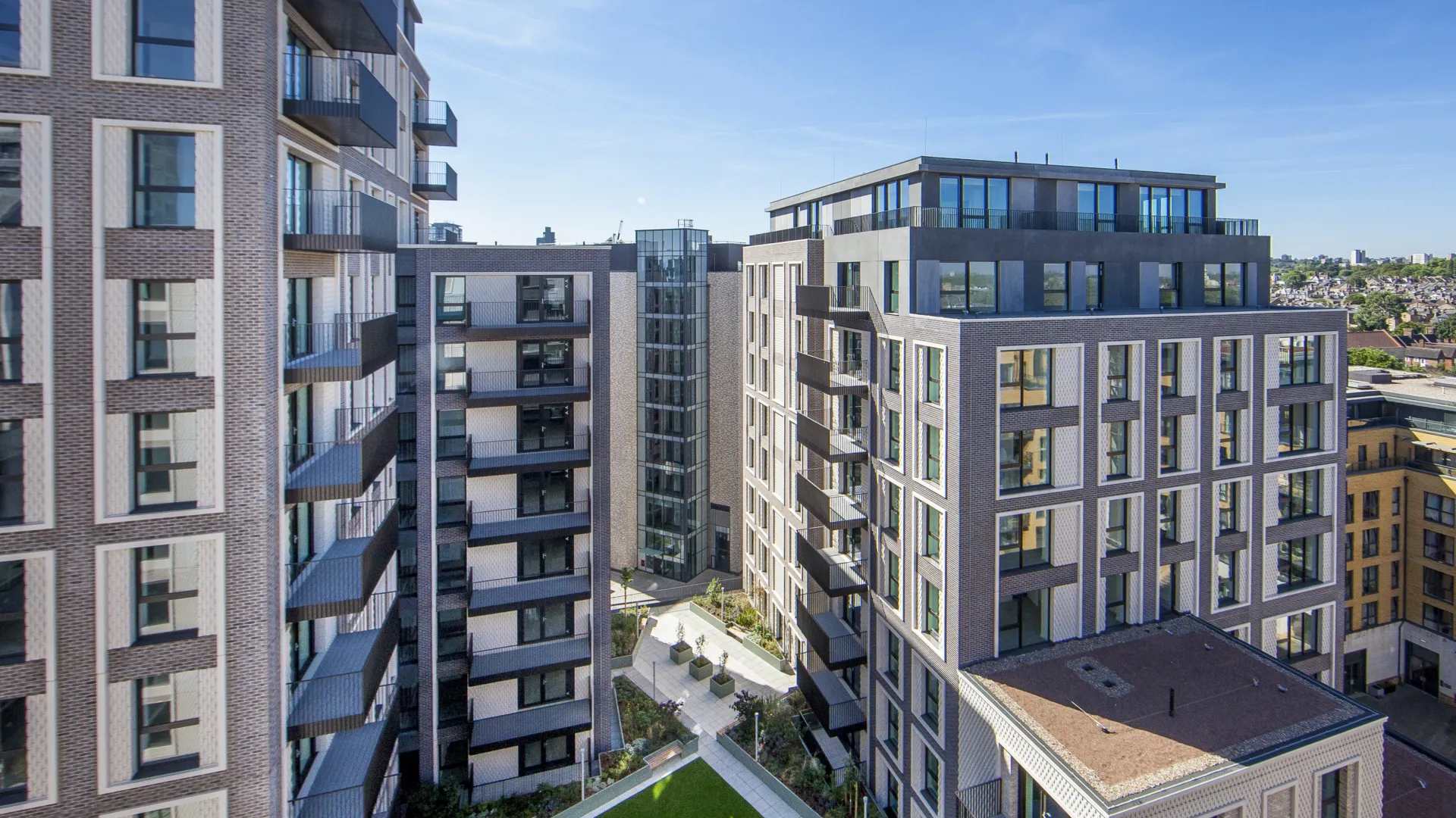 A large residential development from a high vantage point, showing a raise lawned area, balconies, and reflections cast from windows.