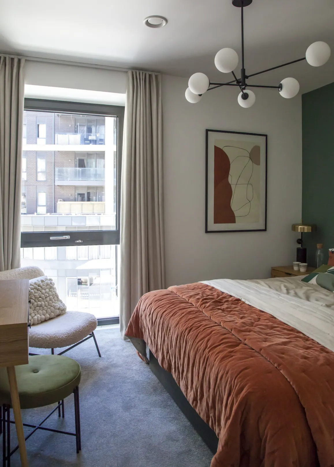 This is a cozy and modern bedroom with neutral colors and a pop of terracotta.