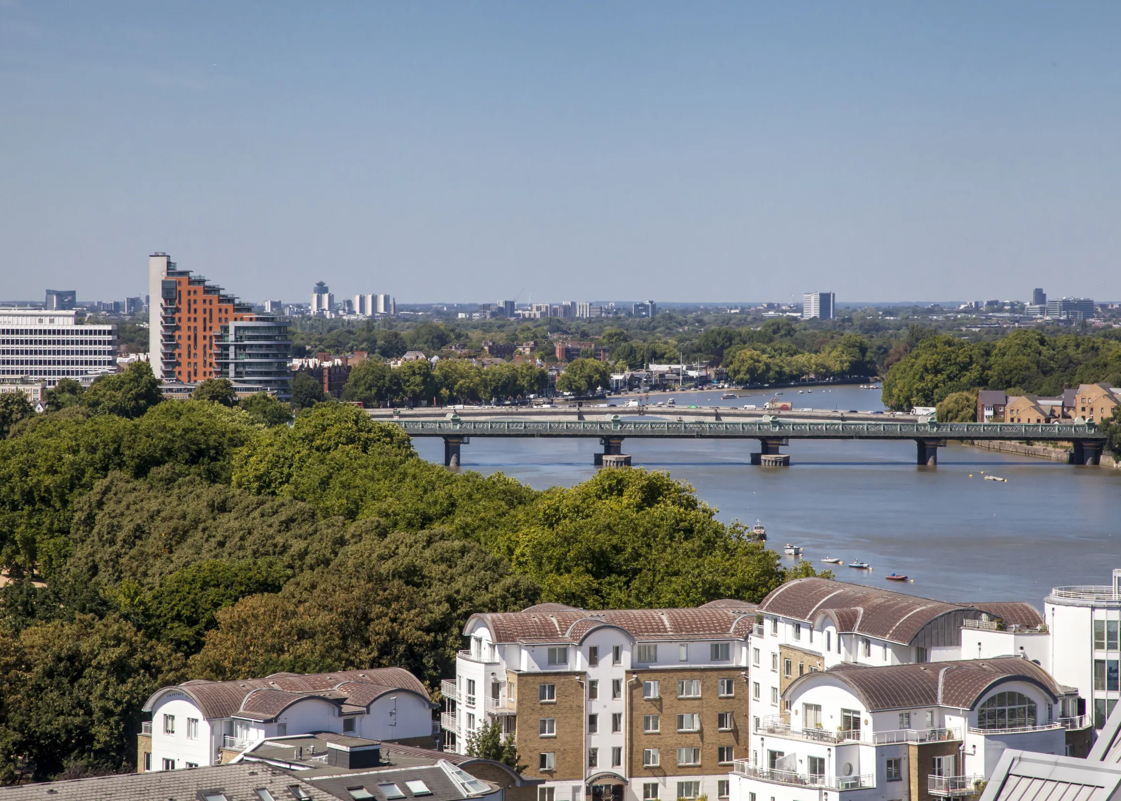 A wide shot of a cityscape with a river and a bridge spanning it.