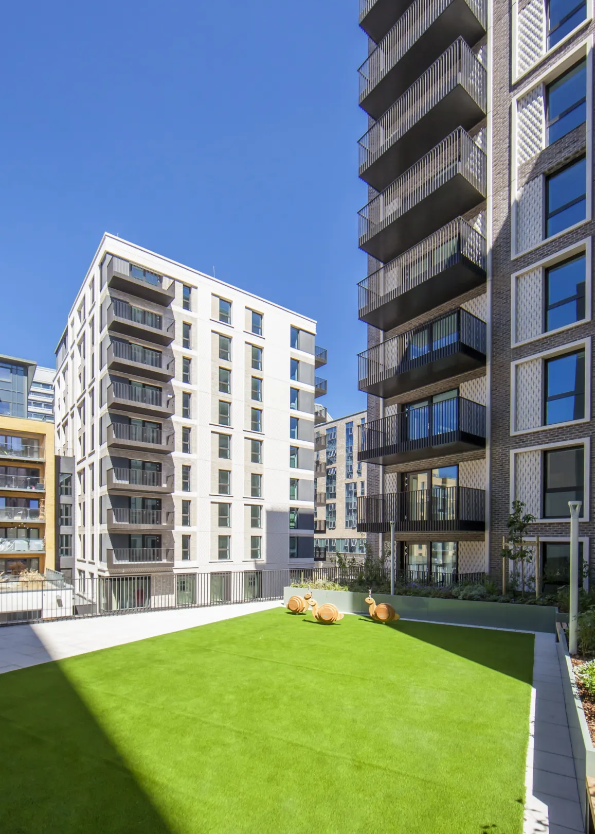 A lawned area in front of two modern residential buildings