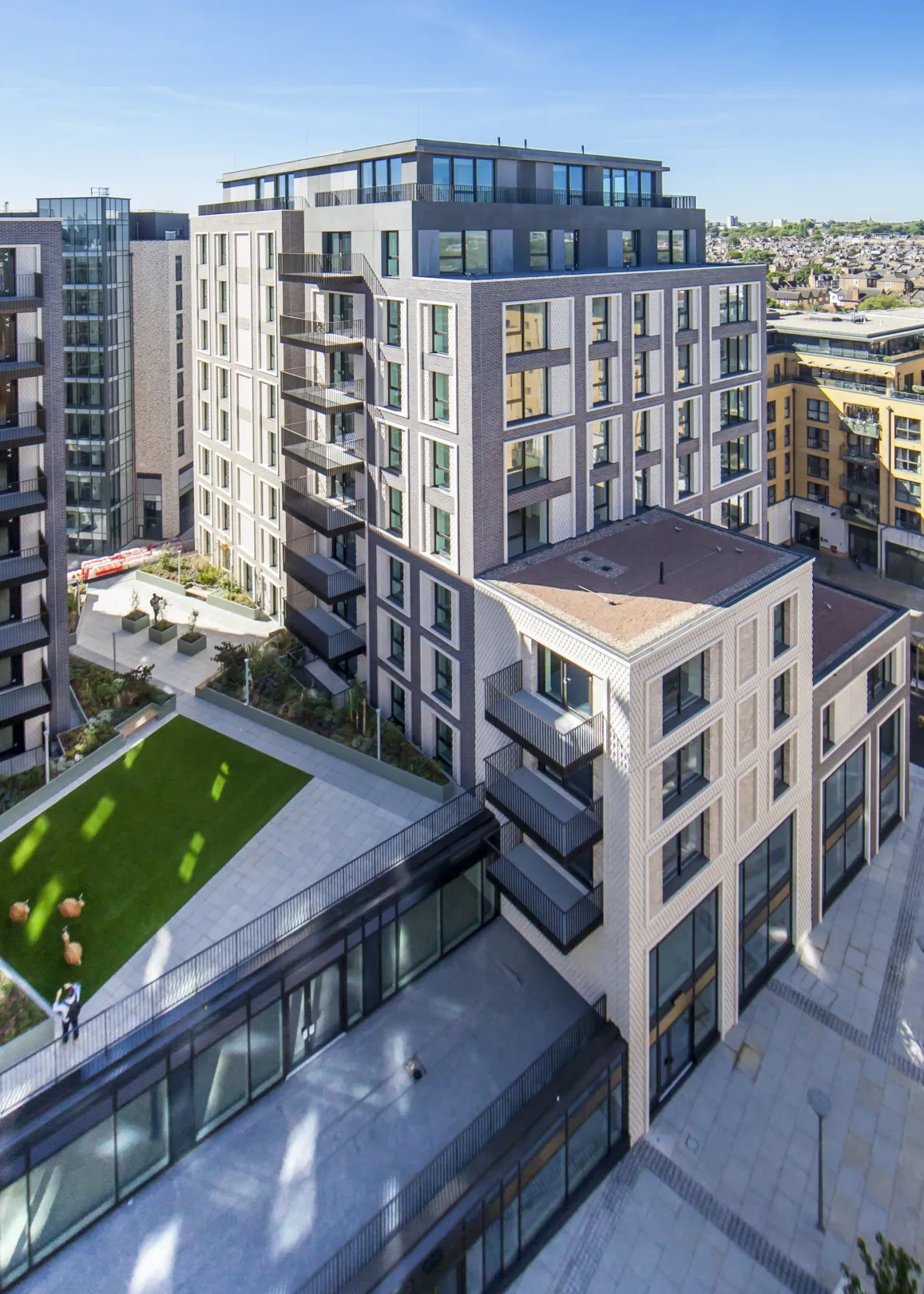 A large residential development from a high vantage point, showing a raise lawned area, balconies, and reflections cast from windows.