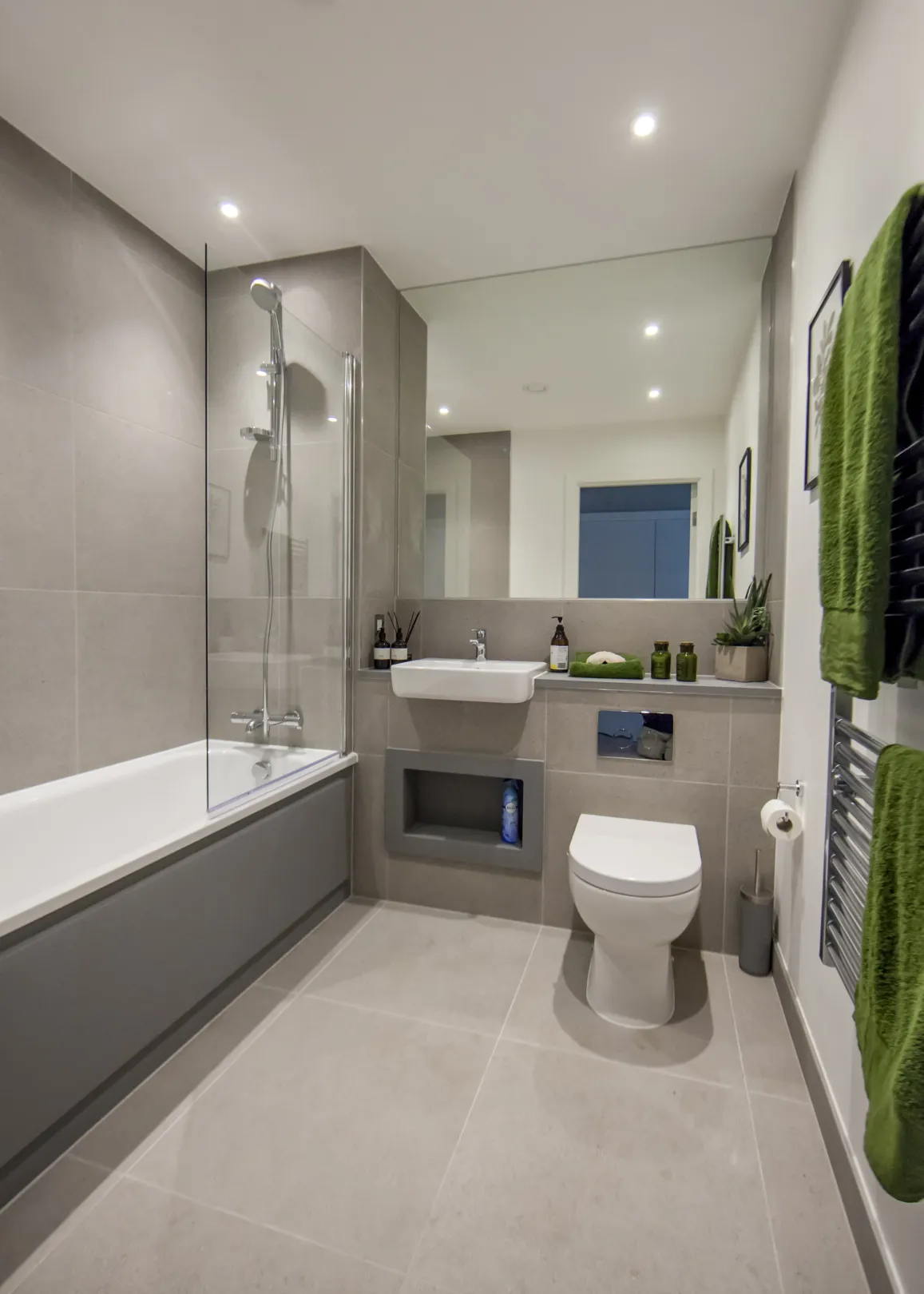 Modern bathroom interior with glazed shower screen, large mirror and heated towel rail