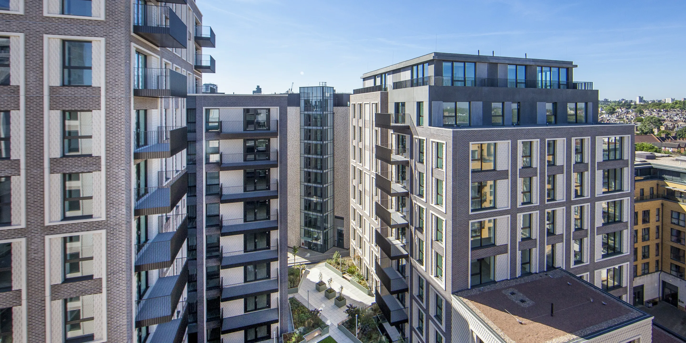 A large residential development from a high vantage point, showing a raise lawned area, balconies, and reflections cast from windows.