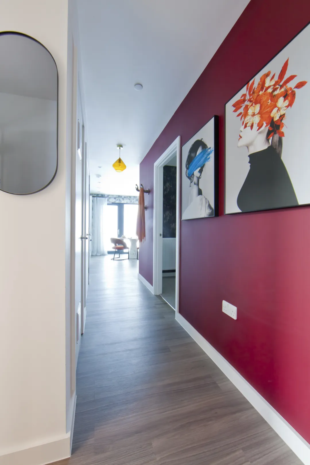 A hallway of a new build aparment with a magenta colour feature wall and hung pictures