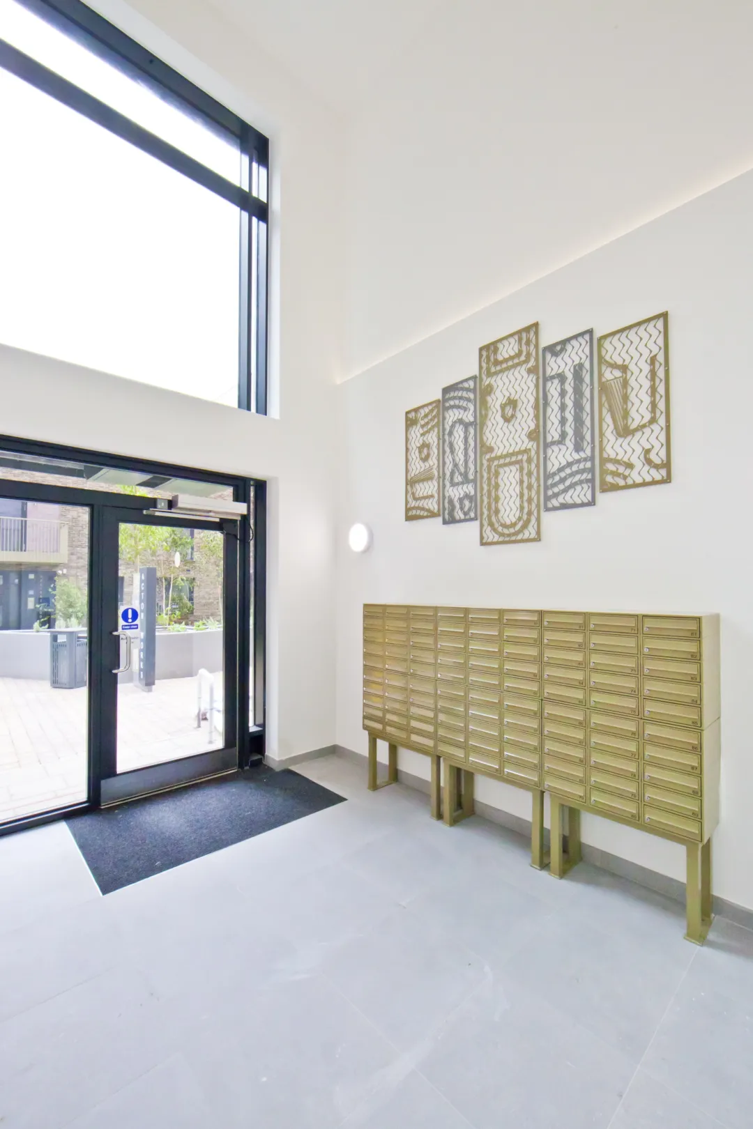 Modern foyer of a residential building showing mailboxes and aft on the wall