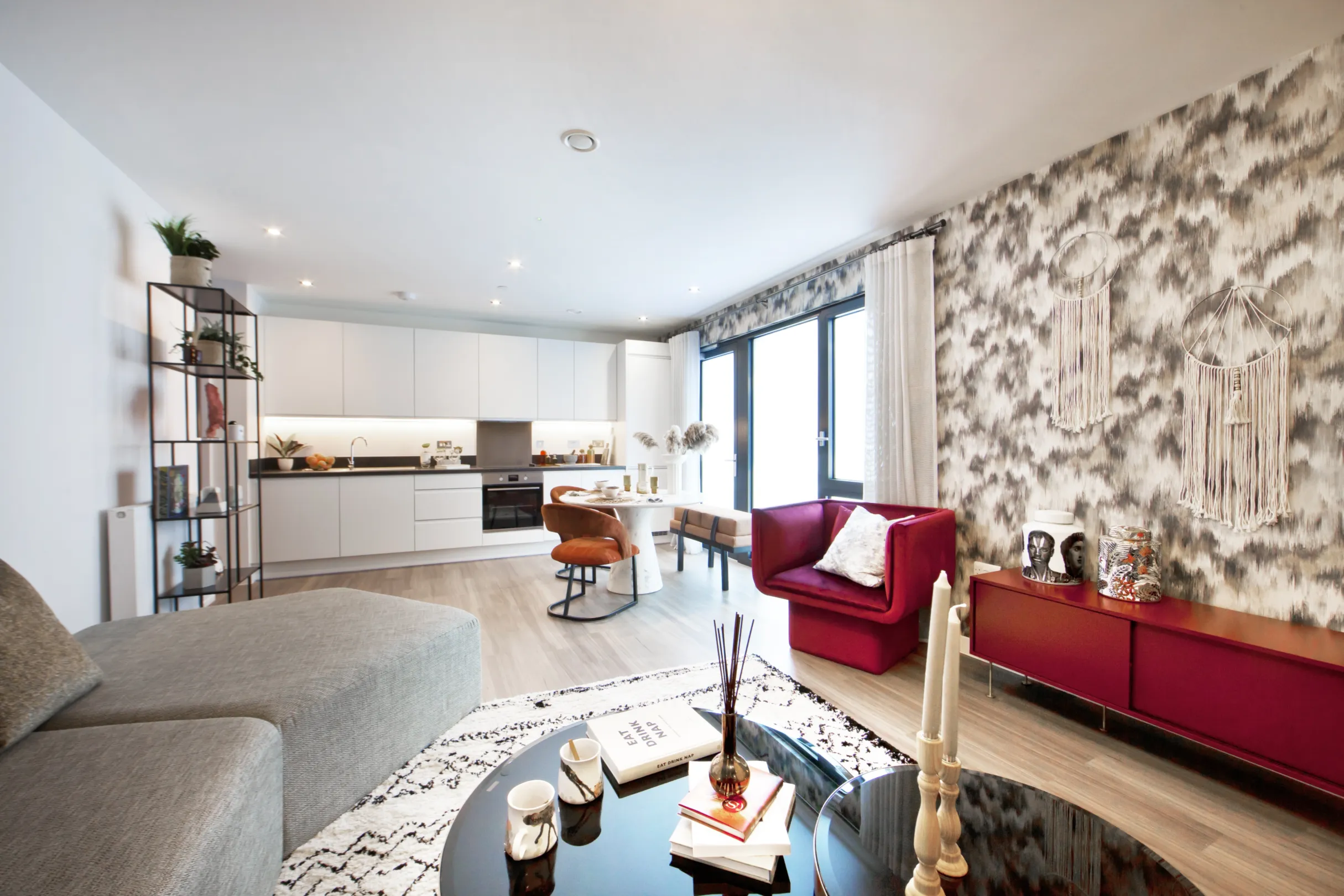 Kitchen and living area in a modern residential building with various items of furniture and ornate wallpaper
