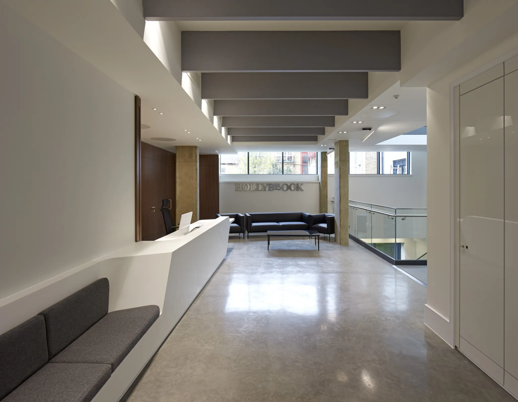 Modern office interior at lower ground level showing glass offices and central staircase in modern ironwork.