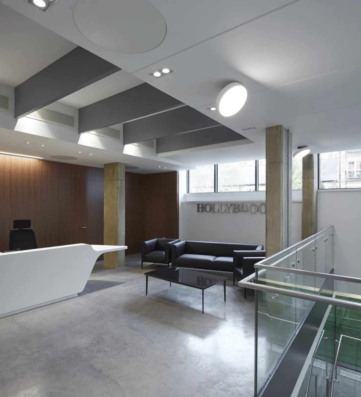 Modern office interior at lower ground level showing glass offices and central staircase in modern ironwork.