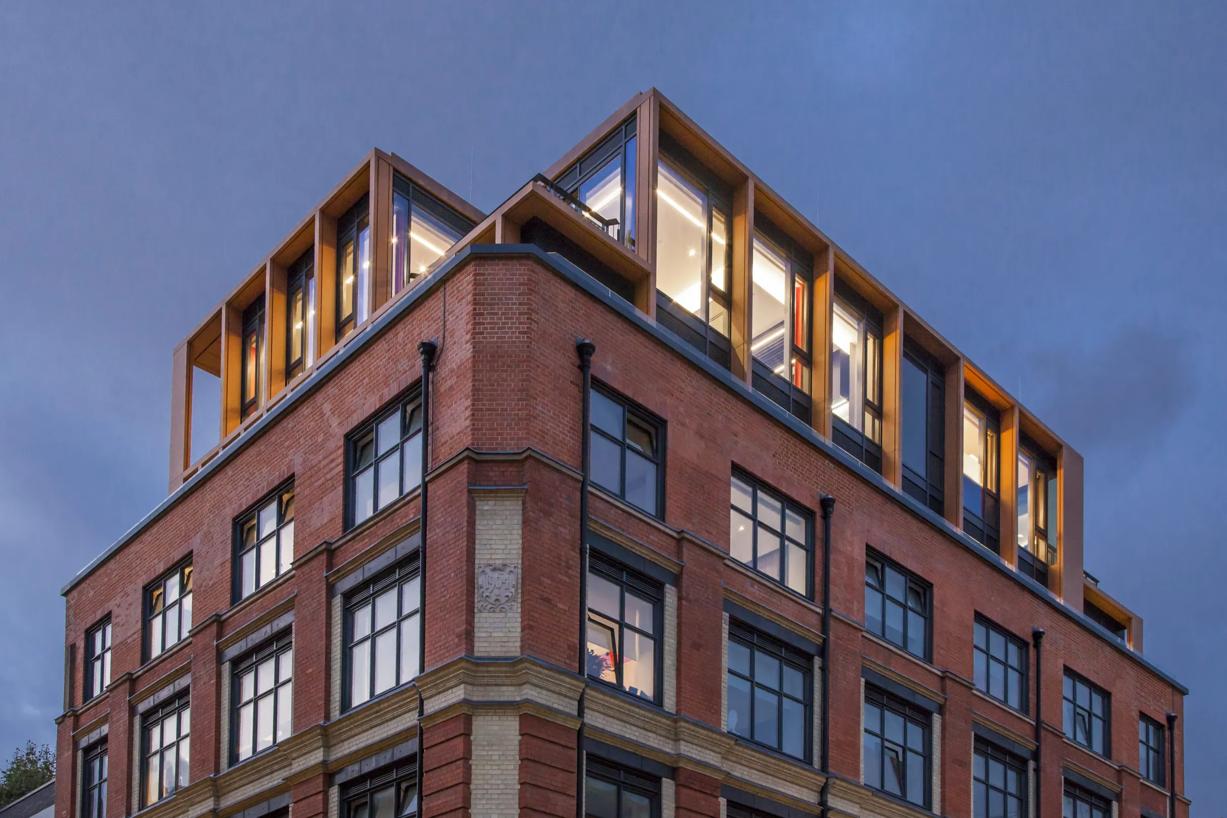 A large brick facade residential building with floor to ceiling windows at penthouse level