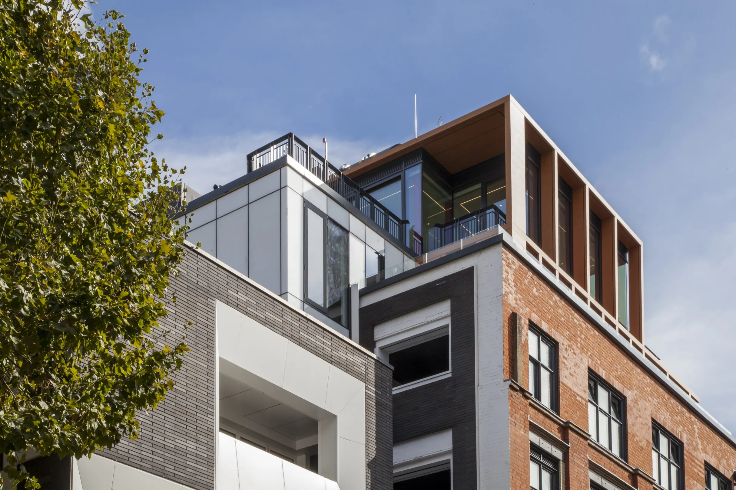 Top floors of a modern residential building, showing large windows and balconies at penthouse level.