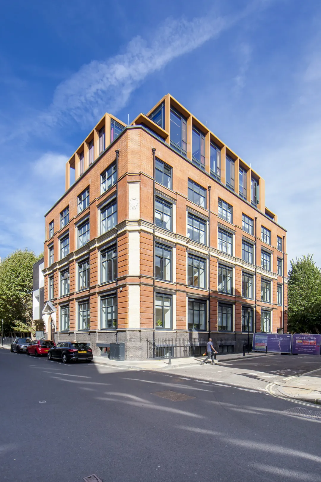 A modern residential block occupying a corner of a London street with card parked down one side