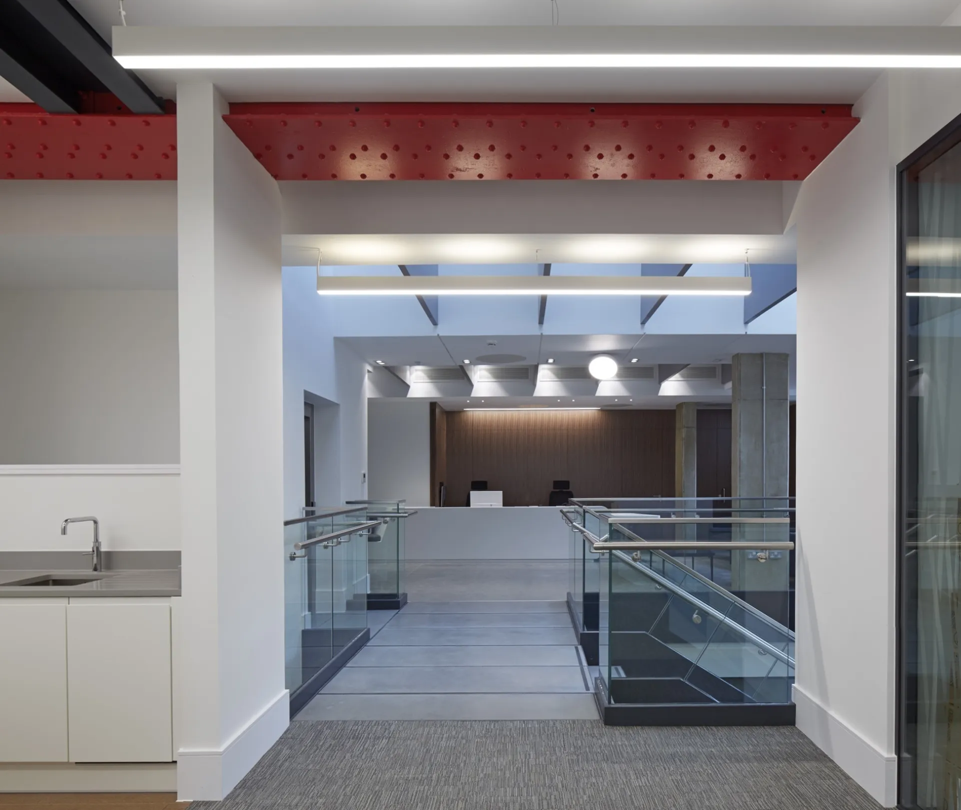 Modern office interior with staircase, kitchenette, reception area and designer lighting.