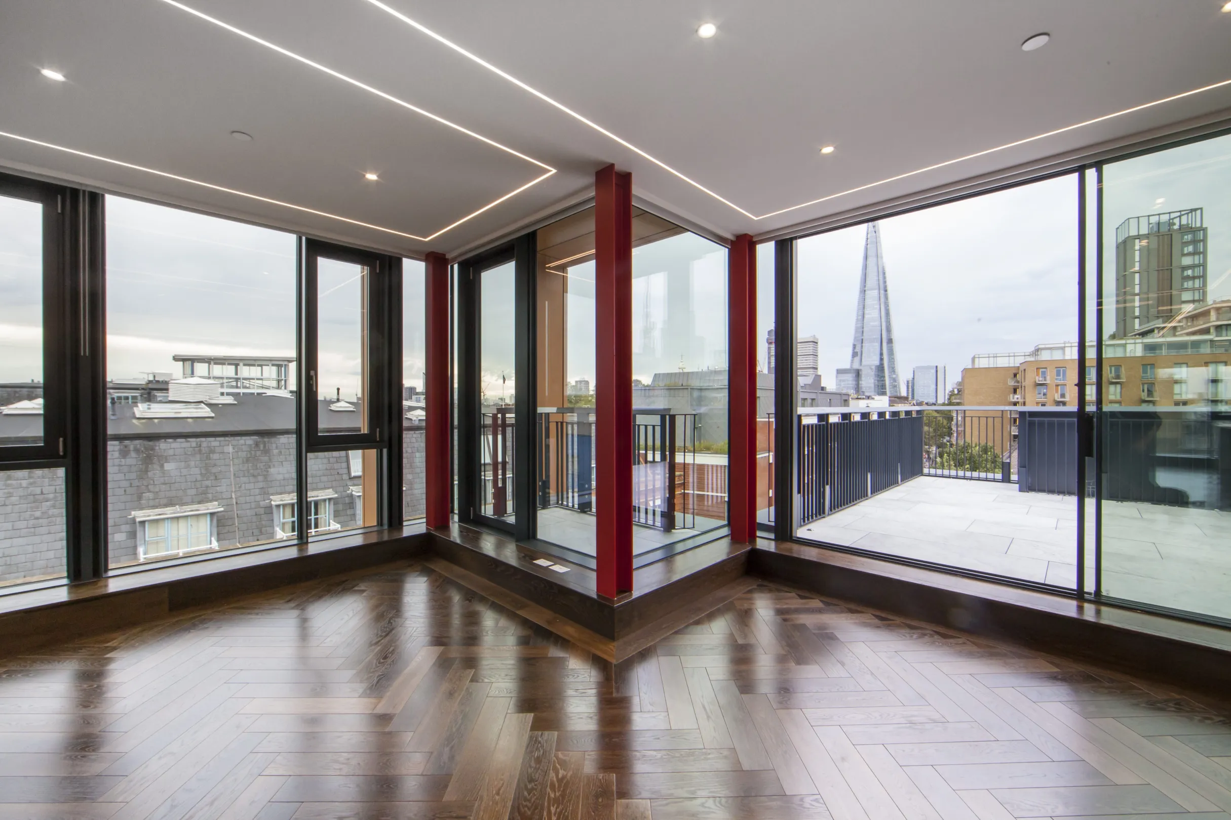 Luxury interior of a dual aspect apartment with floor to ceiling windows leading to a corner balcony and roof terrace. the shard is in the far distance.