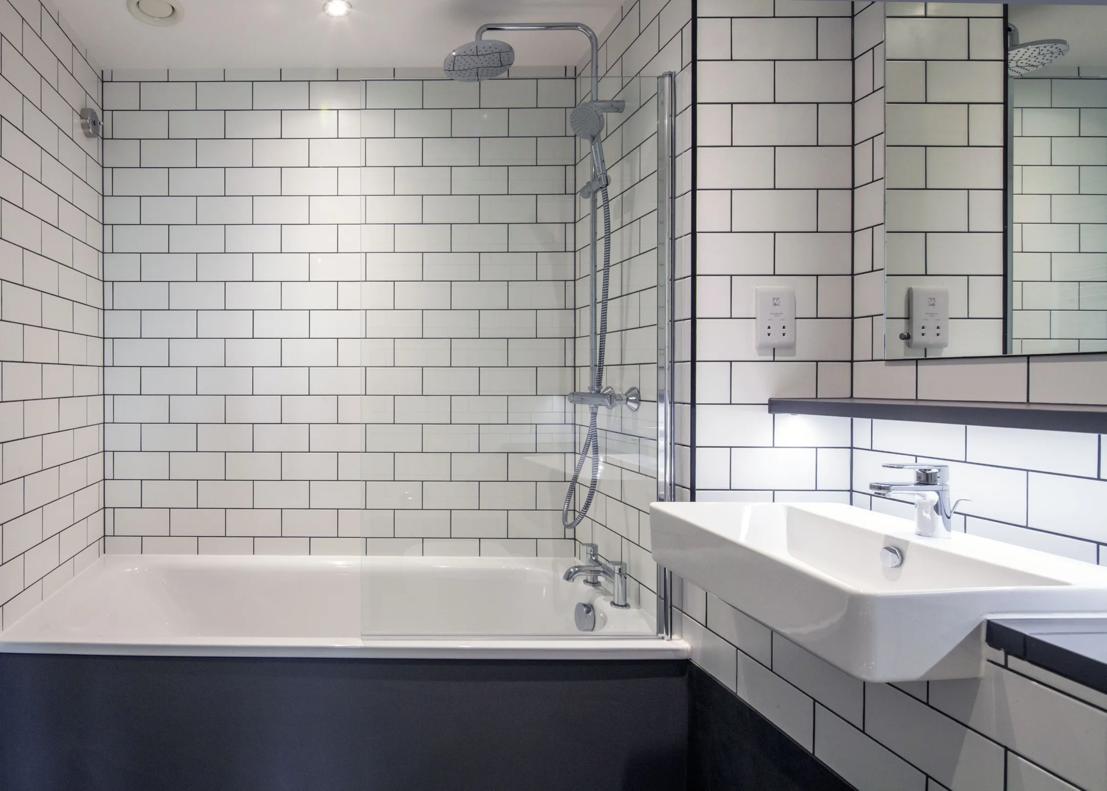 Modern bathroom interior with white tiling and large vanity mirror