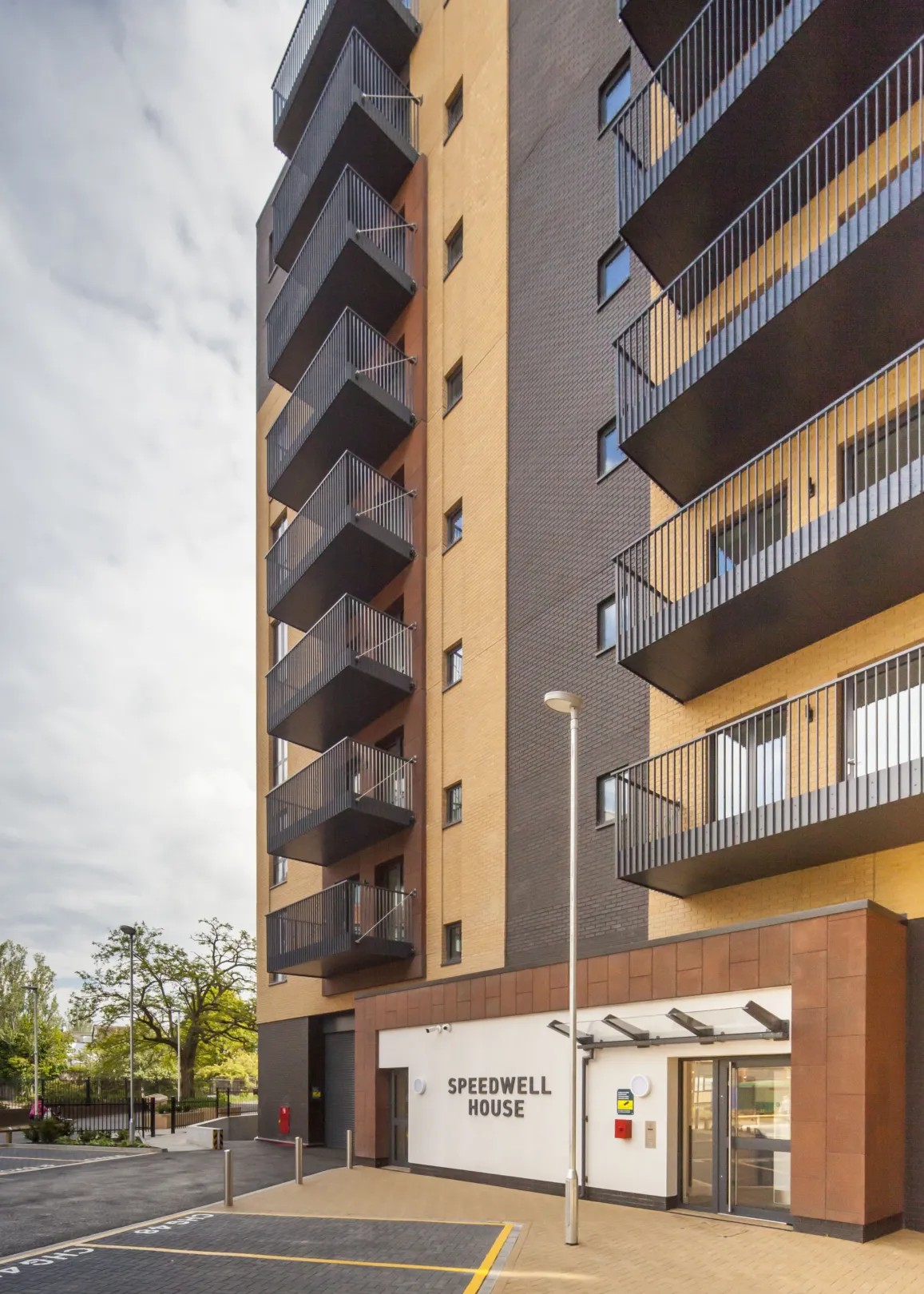 View from ground level of a modern residential building with balconies from the first floor up