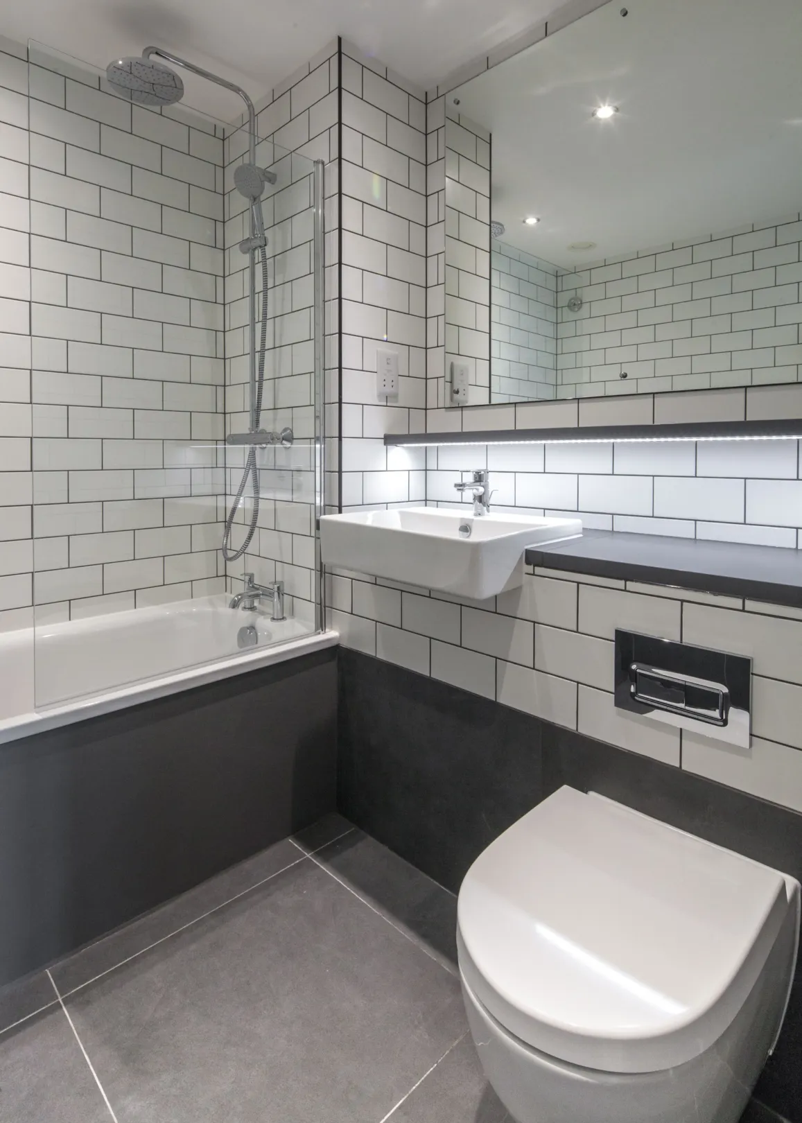Modern bathroom interior with white tiling and large vanity mirror