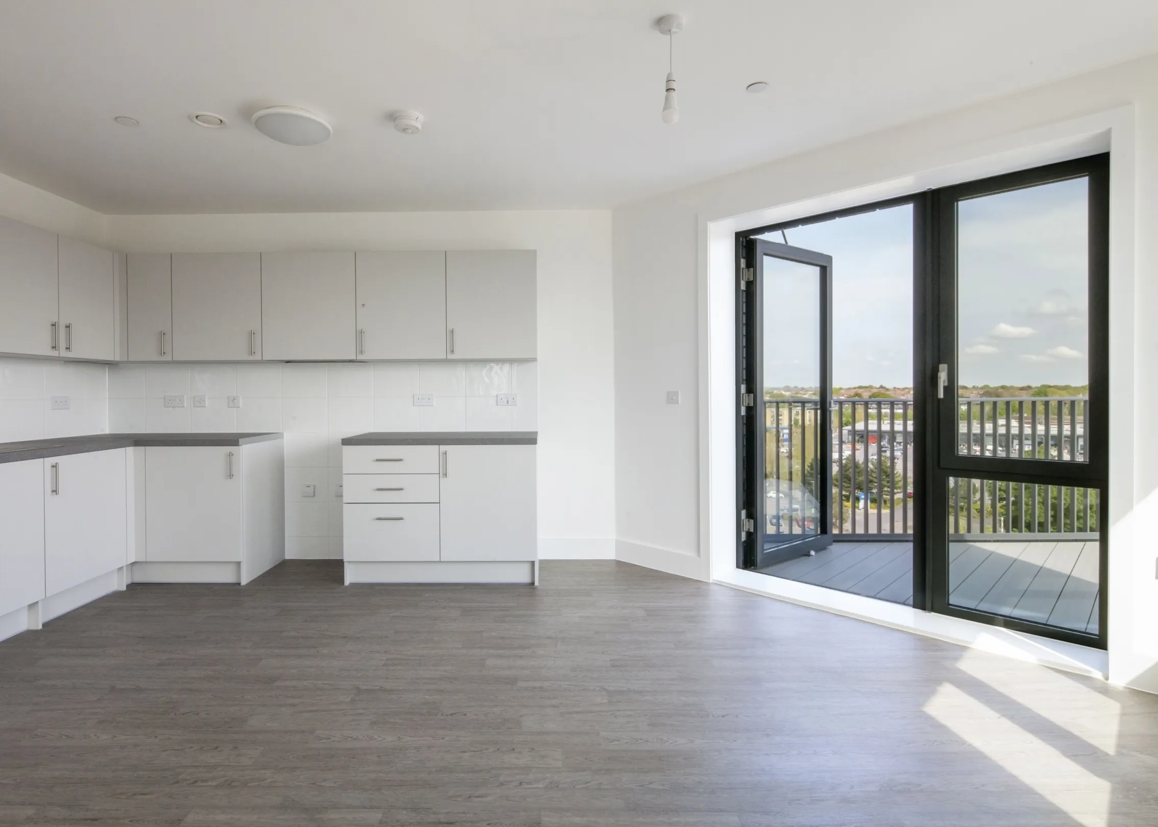 Modern interior living space showing kitchen and glazed windows looking out to a balcony