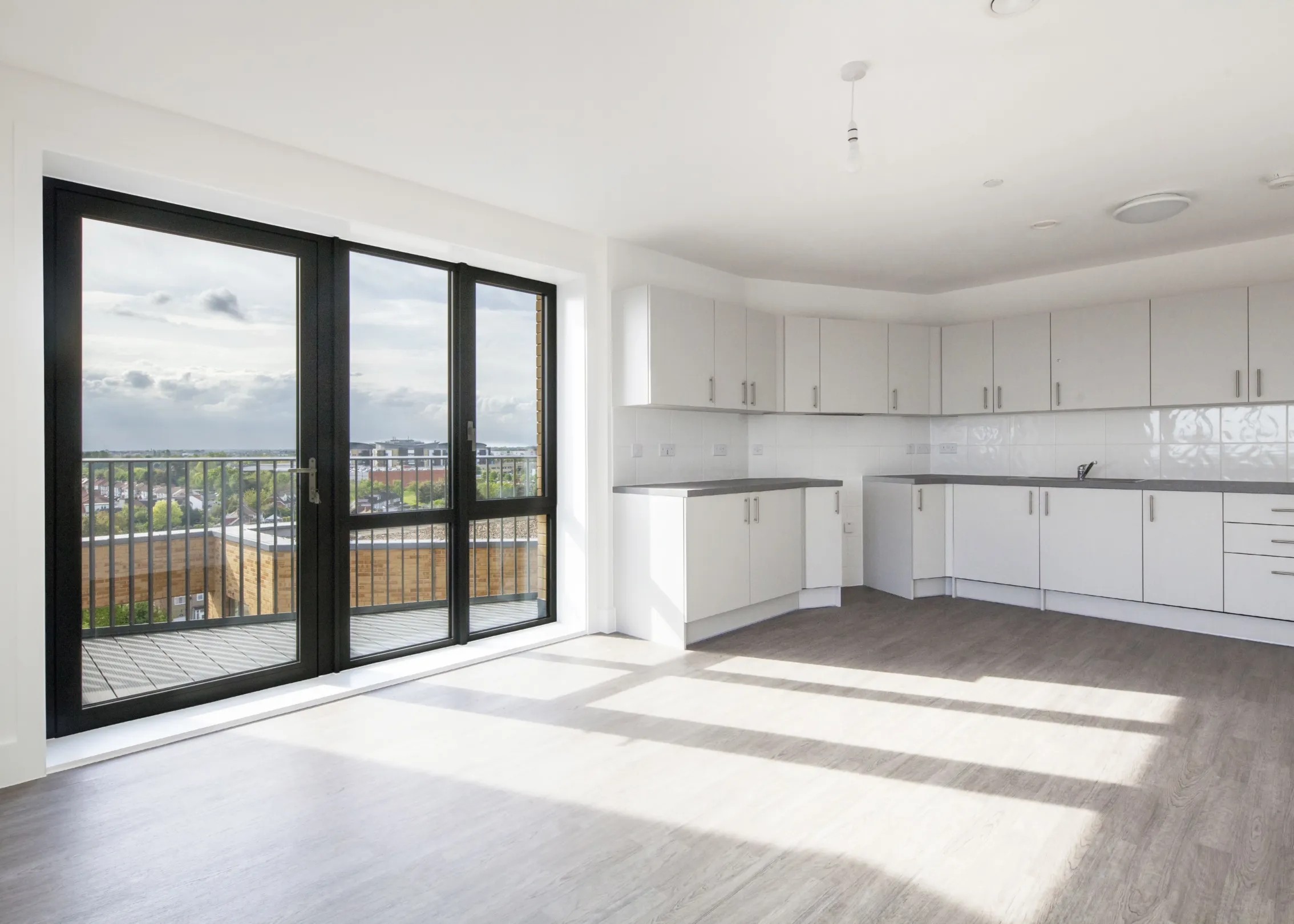 Modern interior living space showing kitchen and glazed windows looking out to a balcony